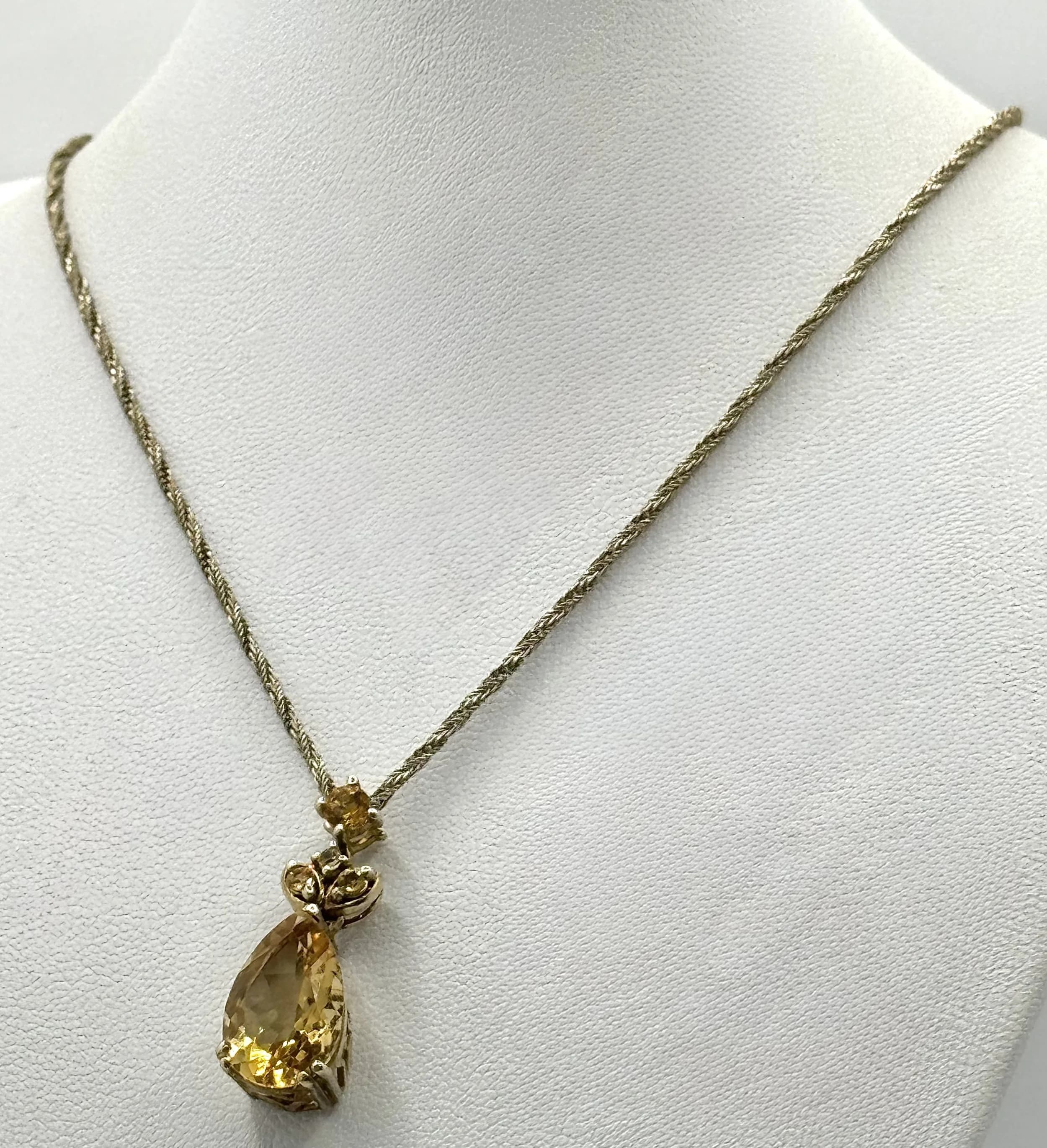 A Pretty Gold-tone 925 Silver Citrine Pendant Necklace - 32cm Length. Features a pear cut faceted citrine stone in a decorative silver setting on a fine silver chain. The pendant drop measures 2.5cm. Gross weight 6.62 grams.