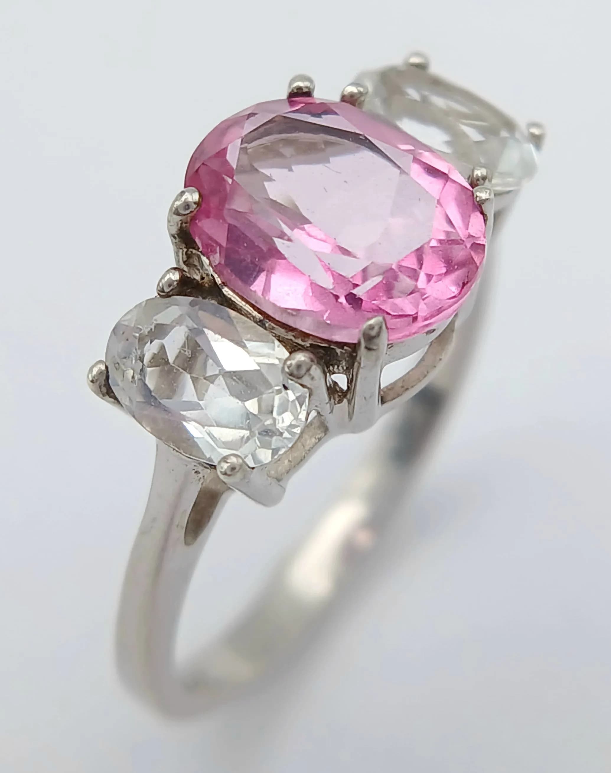 A Sterling Silver Pink and White Topaz Trilogy Ring Size L1/2. The Centre Pink Topaz Measures 9 x 7mm, approximately 2 Carat and Each Side set with White Topaz that measure 6 x 4mm, approximately 0.50 Carat each. The Ring weighs 2.53 grams.