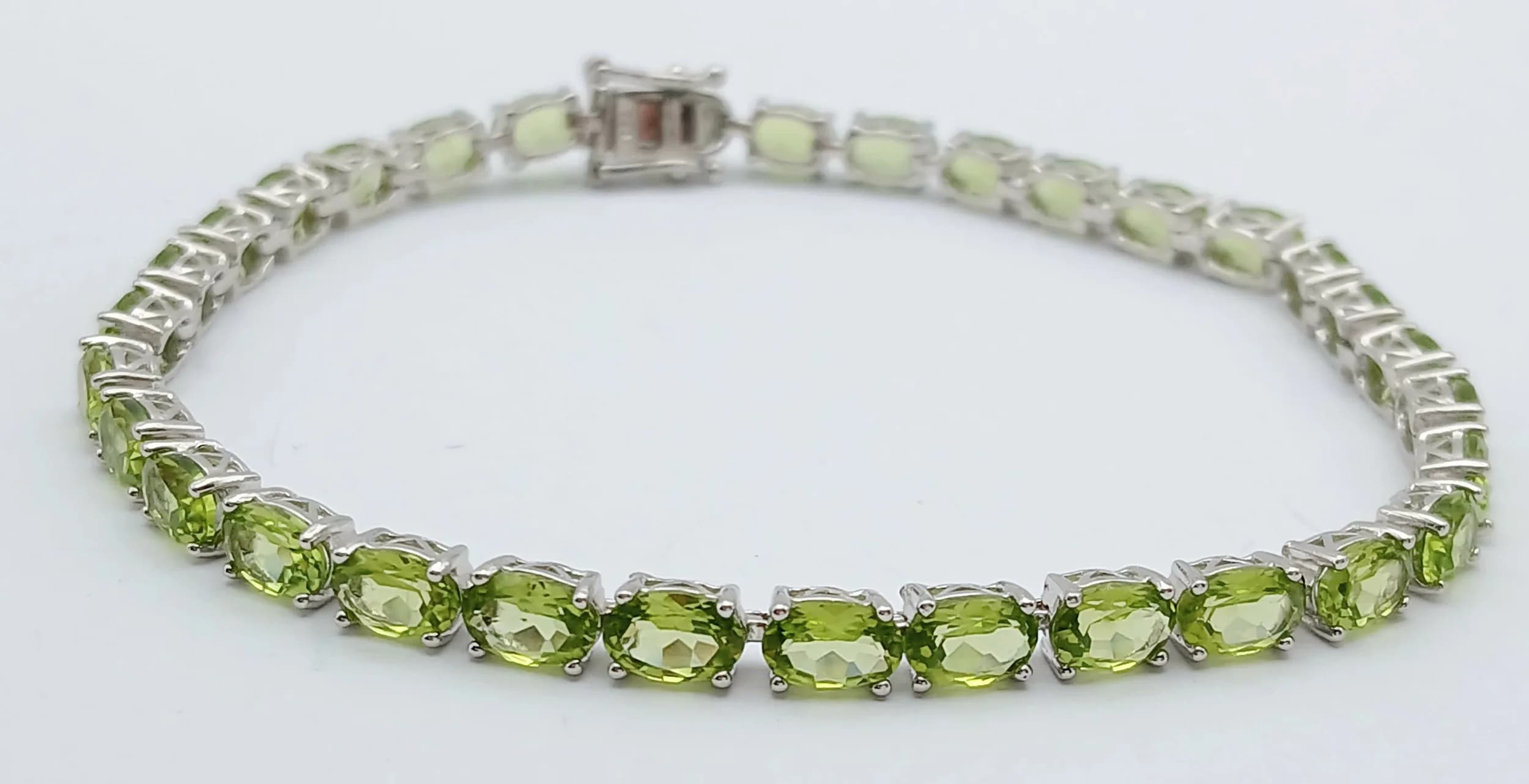 An Elegant Sterling Silver Peridot Set Tennis Bracelet-20cm Length. Set with Thirty-Two 5 x 4mm Oval Cut Peridot, approximately 6.6 carat total GrossWeight 9.75 grams.
