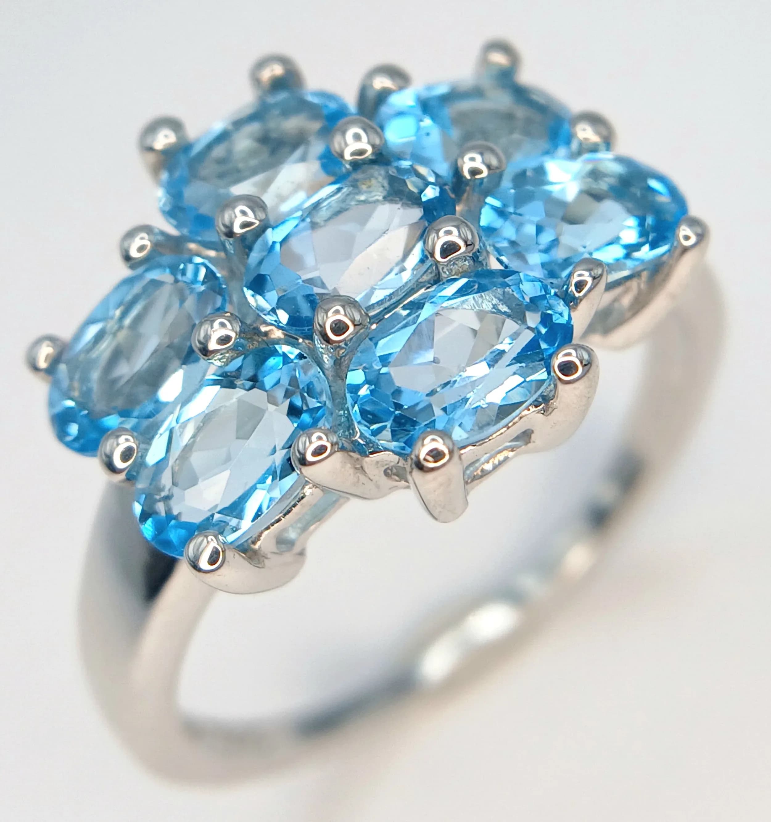 A Sterling Silver Blue Topaz Cluster Ring. Size S. The Ring is set with Seven 6 x 4mm Oval Cut Blue Topaz, totalling approximately 3.5 carat. Gross weight 4.09 grams