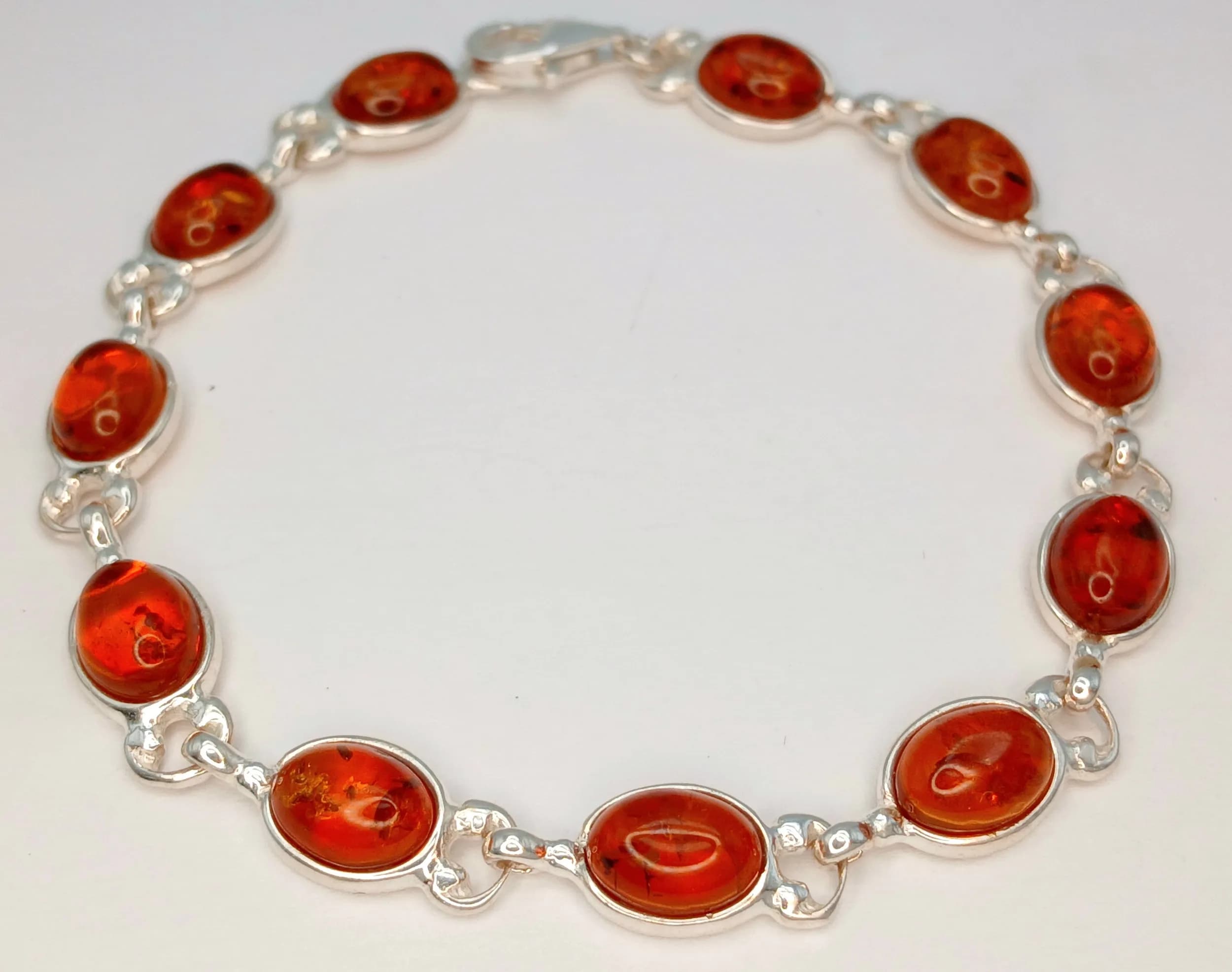 A Baltic Amber 925 Silver Link Bracelet. Measuring 18.5cm in length. Features oval Baltic amber cabochons in a graduated honey to cognac colour, set in articulated silver links. Total weight 8 grams. Made in Poland.