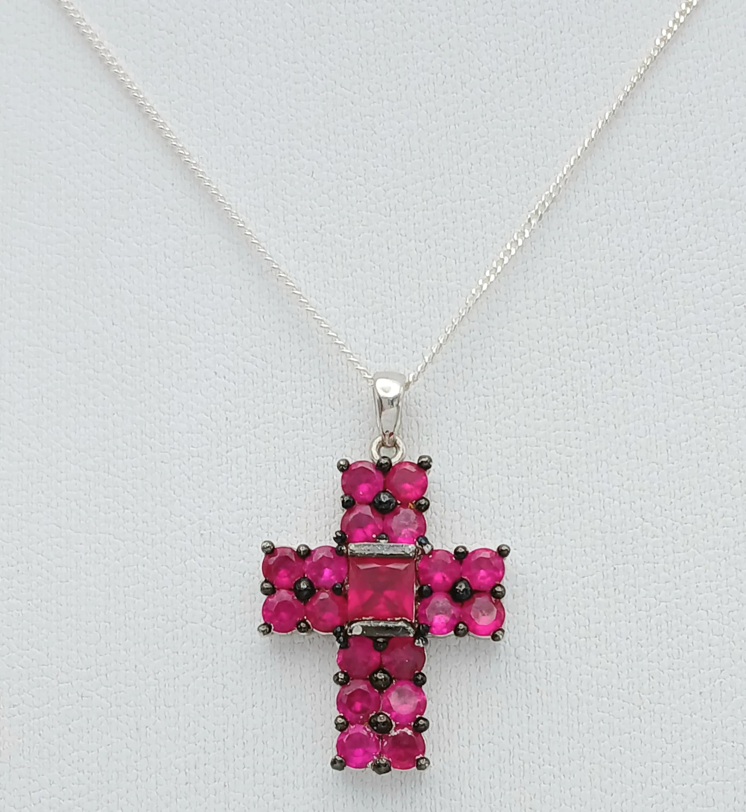 A Pretty Sterling Silver Ruby Set Cross Pendant Necklace-46cm Length. The Cross is set with a Centre 4mm Square Cut Ruby and with Eighteen 3mm Round Cut Rubies, approximately 3 carat total. The Necklace has a grossweight of 5.8 grams.
