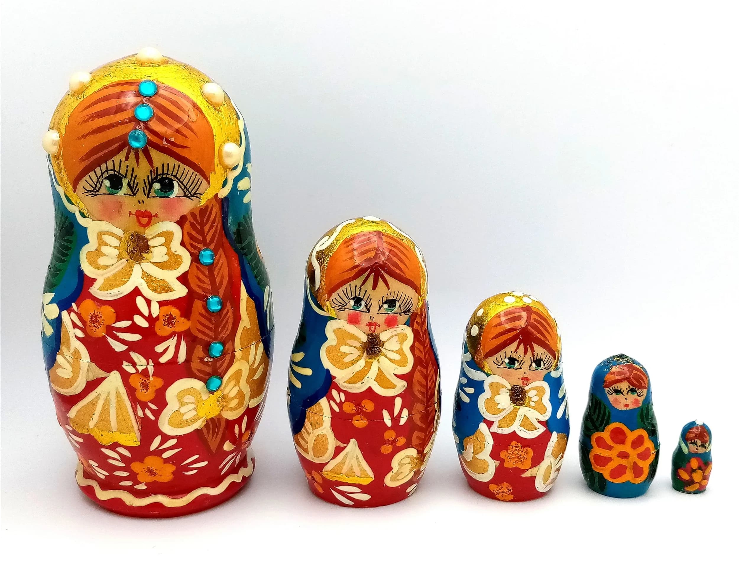 A Traditional Beaded Russian Nesting Doll Set. Five-piece hand-painted wooden nesting doll set featuring a multi-colour floral design with applied bead decoration. Handmade in Russia. Tallest doll measures 11cm. All dolls fit inside each other.