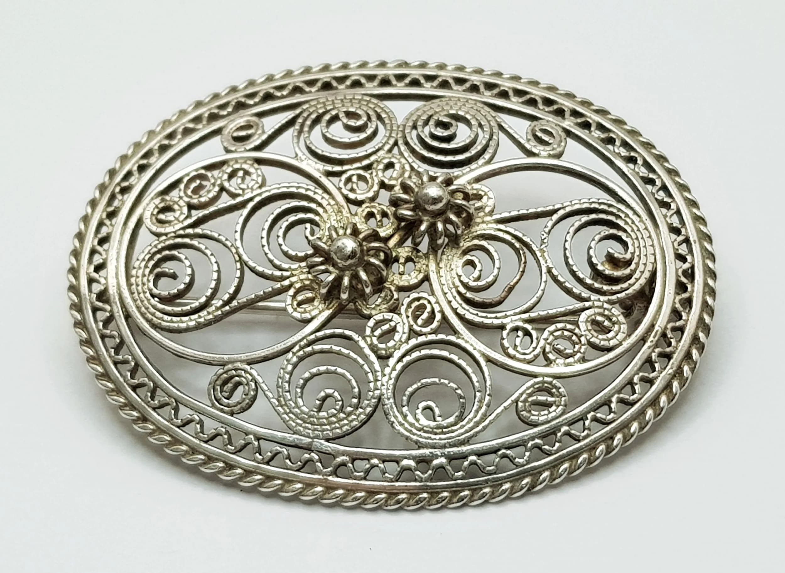 A Vintage Silver Filigree Brooch. Features an oval openwork filigree design with a central floral motif and secure pin fastening. The brooch measures 4cm x 3cm. Total weight 5.96 grams.