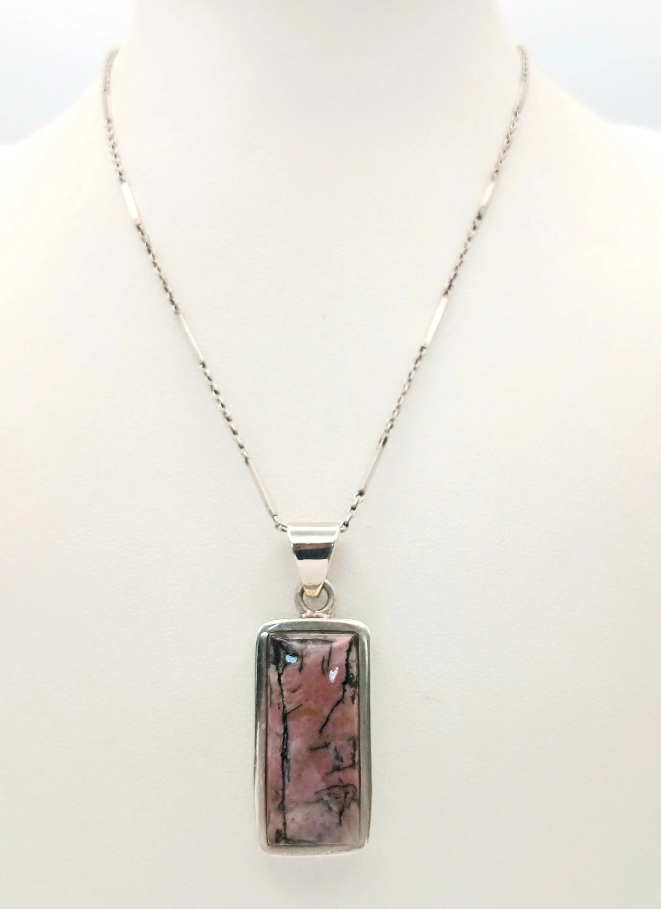 A Vintage Sterling Silver Rhodonite Pendant Necklace. On a 37cm Bar and Link Chain. Comes with an additional 6cm Length Magnetic Clasp Extension. The Pendant measures 2.7cm Length and weighs 16.26 grams.