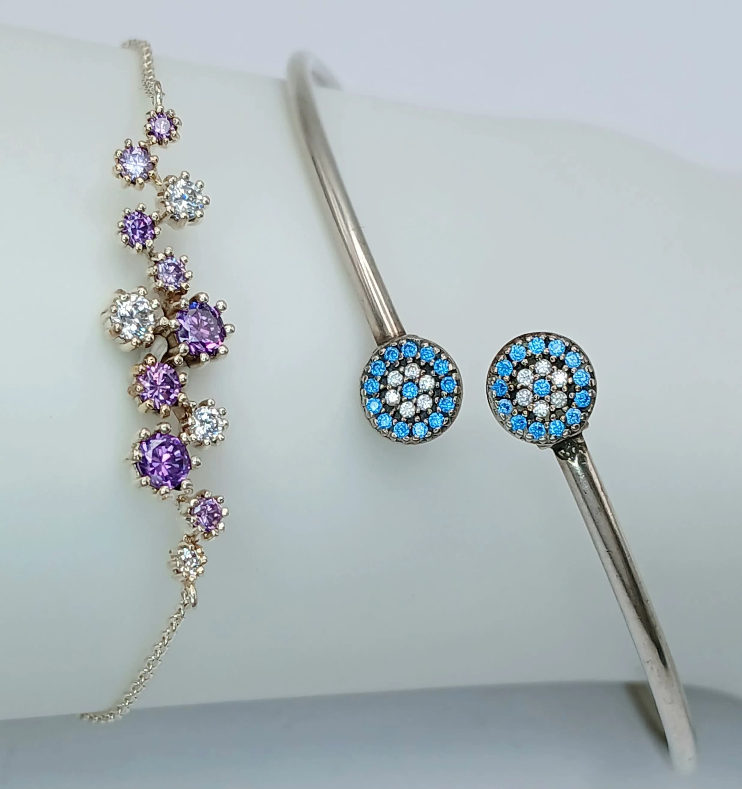 Two Sterling Silver Bracelets. Comprising:1) A Hand Made Sterling Silver Purple and White Stone Daisy Bracelet-Fits 17.5 to 19cm and 2) A Sterling Silver Blue and White Stone Torque Bangle-6.5cm inner width-flexible fit.