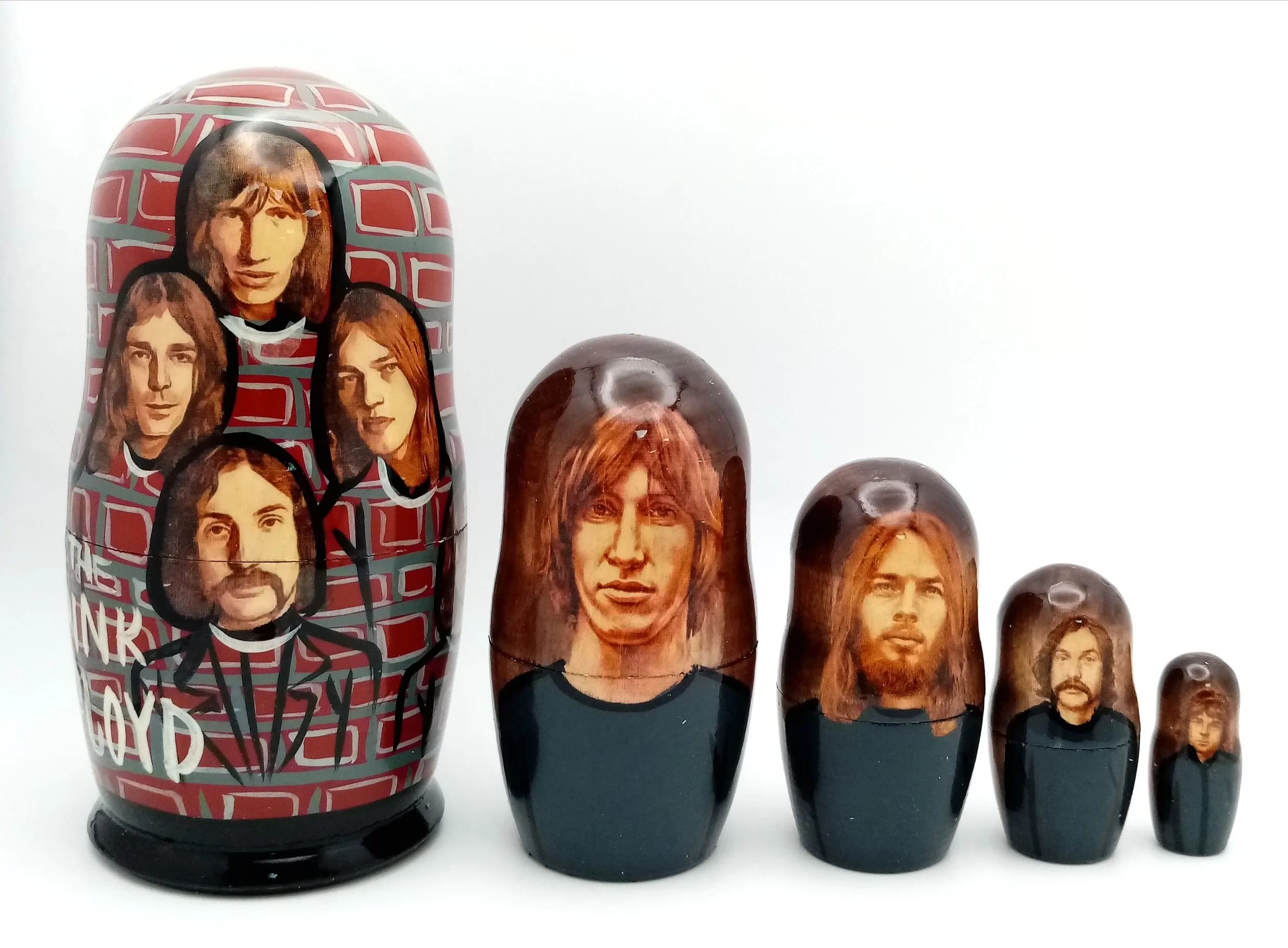 A Pink Floyd Style Russian Nesting Doll Set. Five-piece painted wooden nesting doll set featuring band member portraits. Tallest doll measures 11cm. All dolls fit inside each other.