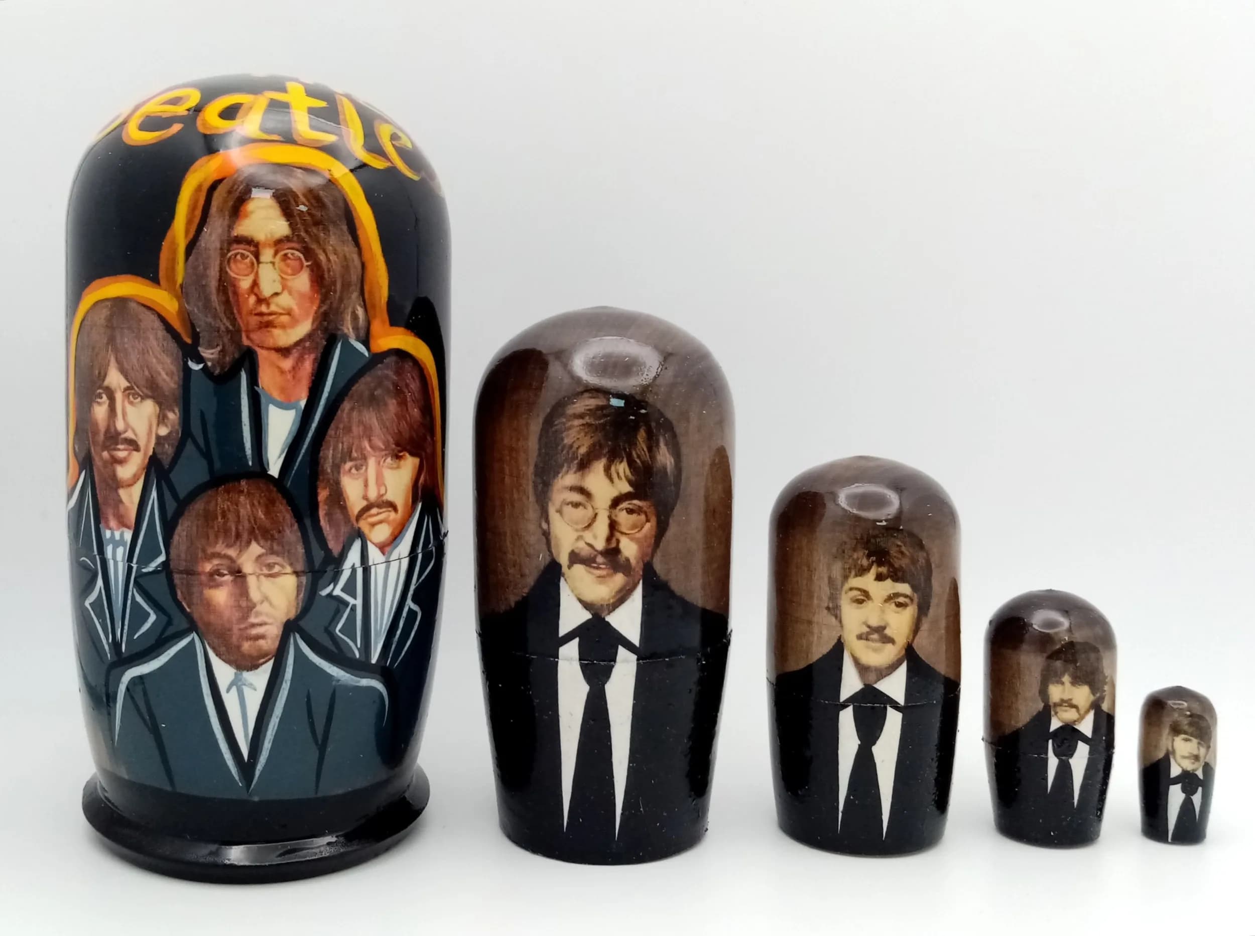 A Beatles Style Russian Nesting Doll Set. Five-piece painted wooden nesting doll set featuring band member portraits. Made in Russia. Tallest doll measures 11cm. All dolls fit inside each other.
