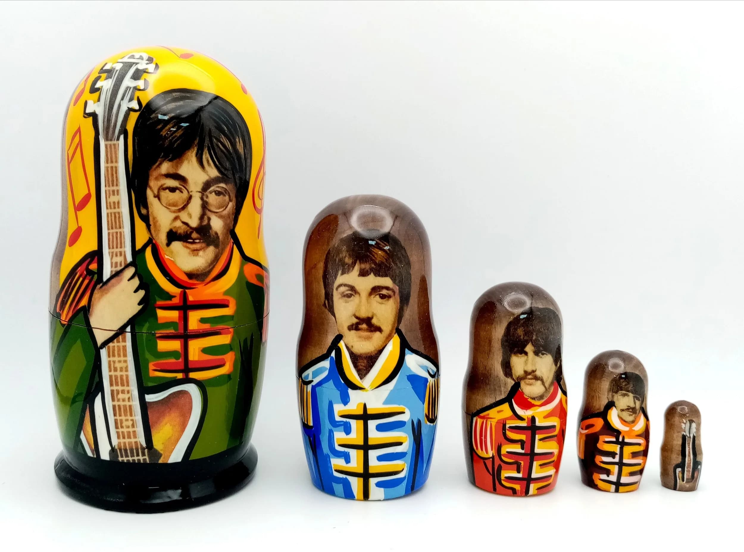 A Sgt. Pepper Style Russian Nesting Doll Set. Five-piece painted wooden nesting doll set featuring Beatles-style Sgt. Pepper figures. Made in Russia. Tallest doll measures 11cm. All dolls fit inside each other.