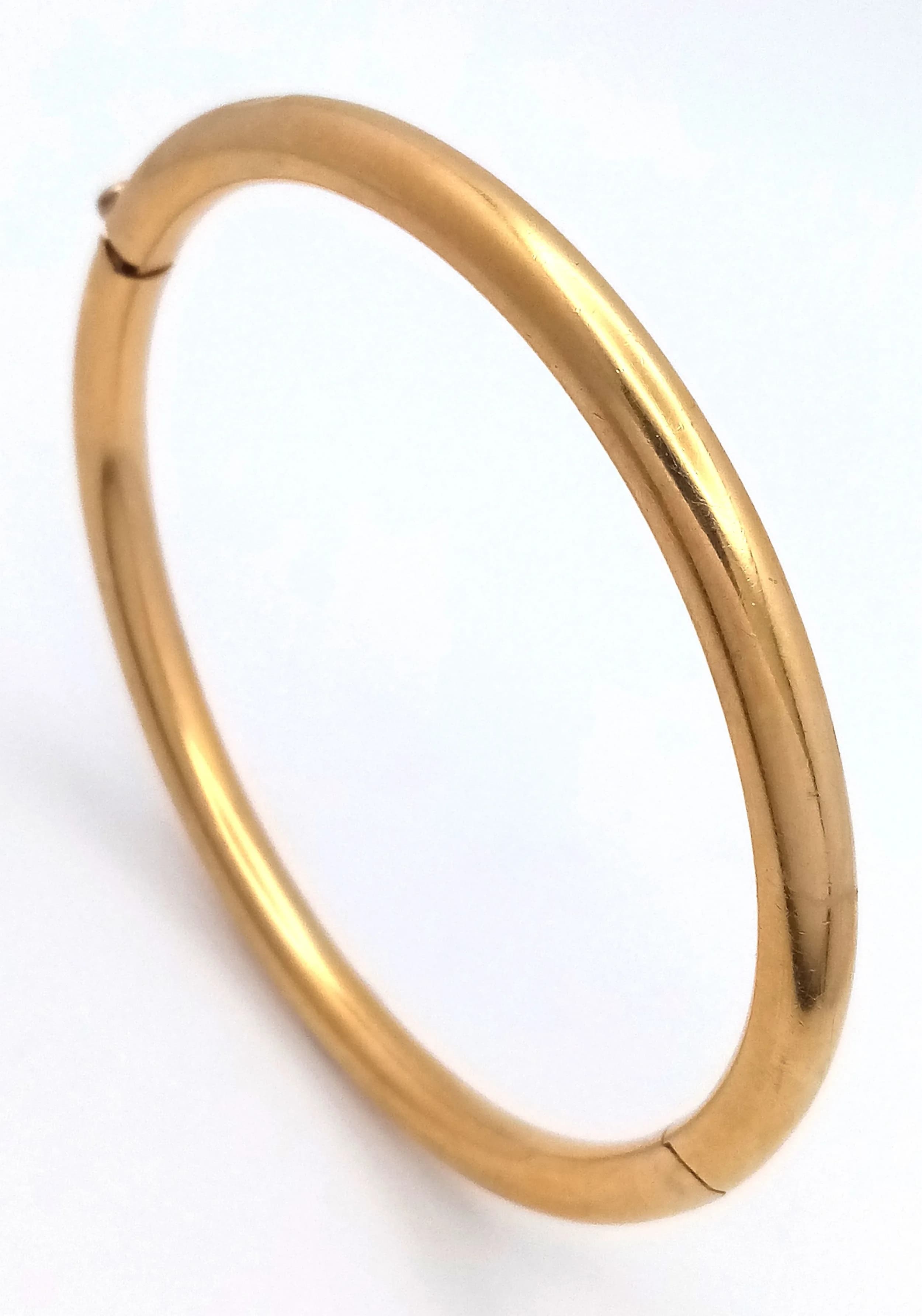 An 18K GOLD CLICK-SHUT HINGED BANGLE. 60mm INNER DIAMETER. 4mm BAND WIDTH. 15g.