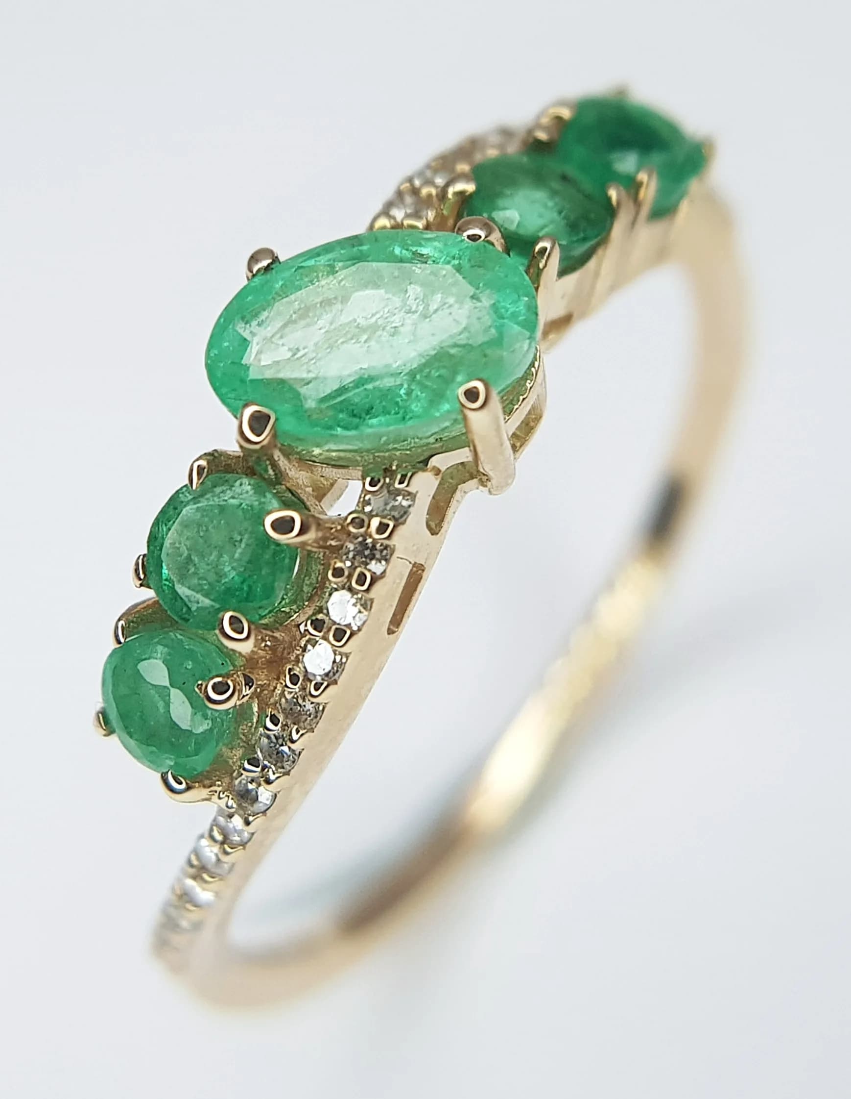 A 14K YELLOW GOLD, 0.94ctw Five Stone Zambian Emerald Ring. 0.86ctw of round and mixed cut emeralds. Size N 1/2. 1.83g total weight. Comes with an HRD of Antwerp certificate. In Excellent condition. CLR-12870.