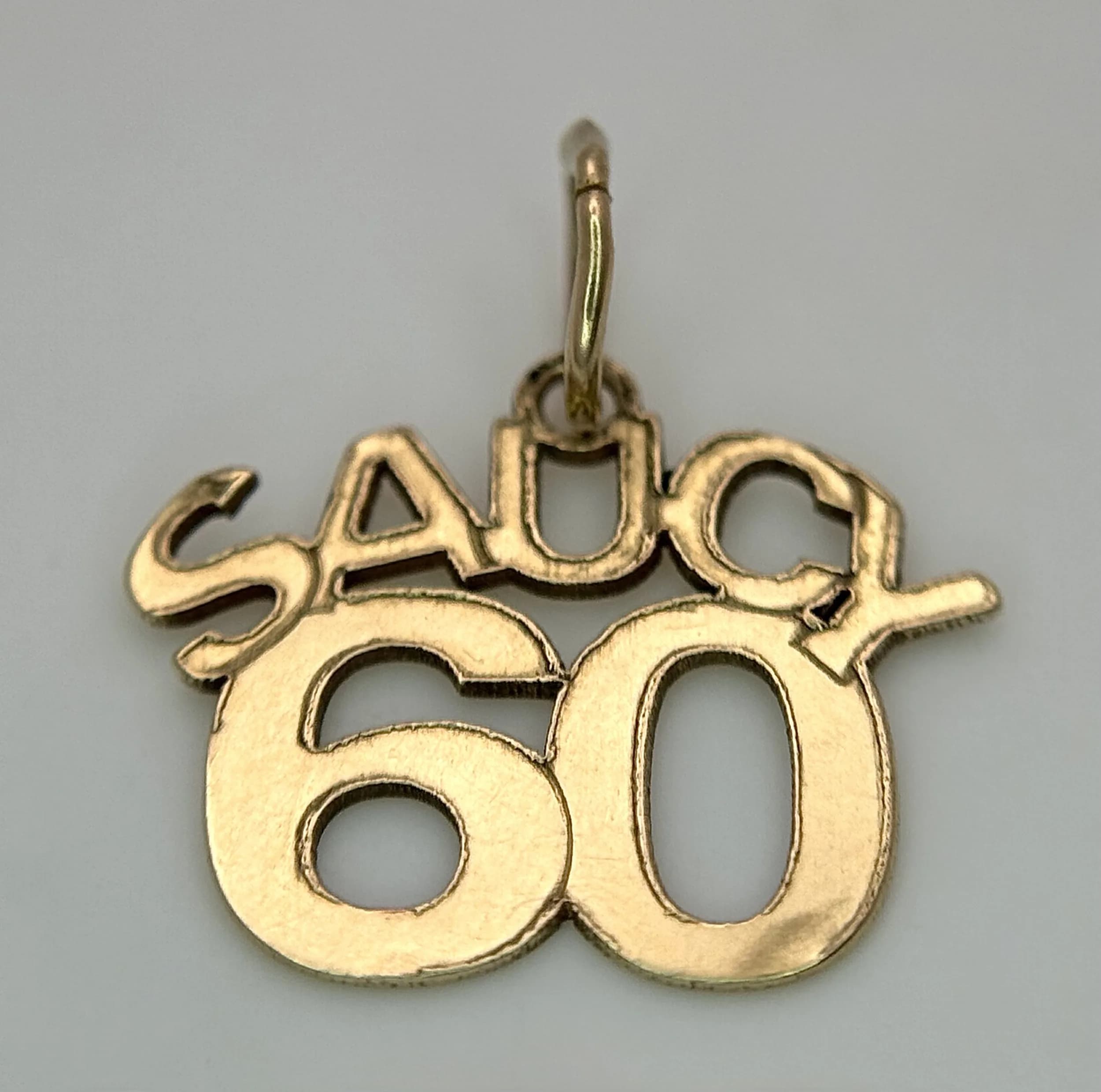 A 9K YELLOW GOLD (TESTED), SAUCY 60, PENDANT / CHARM. 0.4G. SC 5051