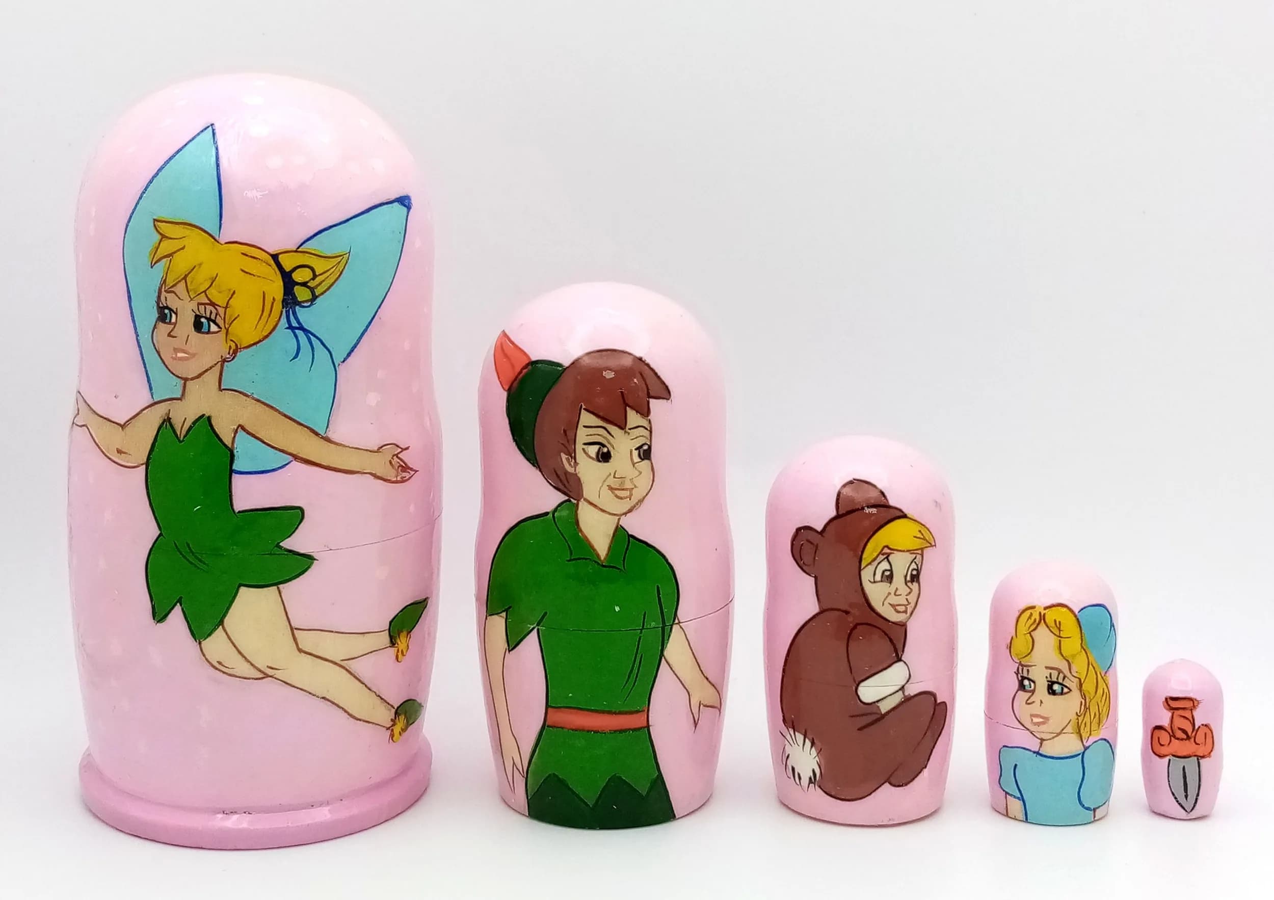 A Tinker Bell Style Russian Nesting Doll Set. Five-piece painted wooden nesting doll set featuring a fairy character design. Made in Russia. Tallest doll measures 11cm. All dolls fit inside each other.