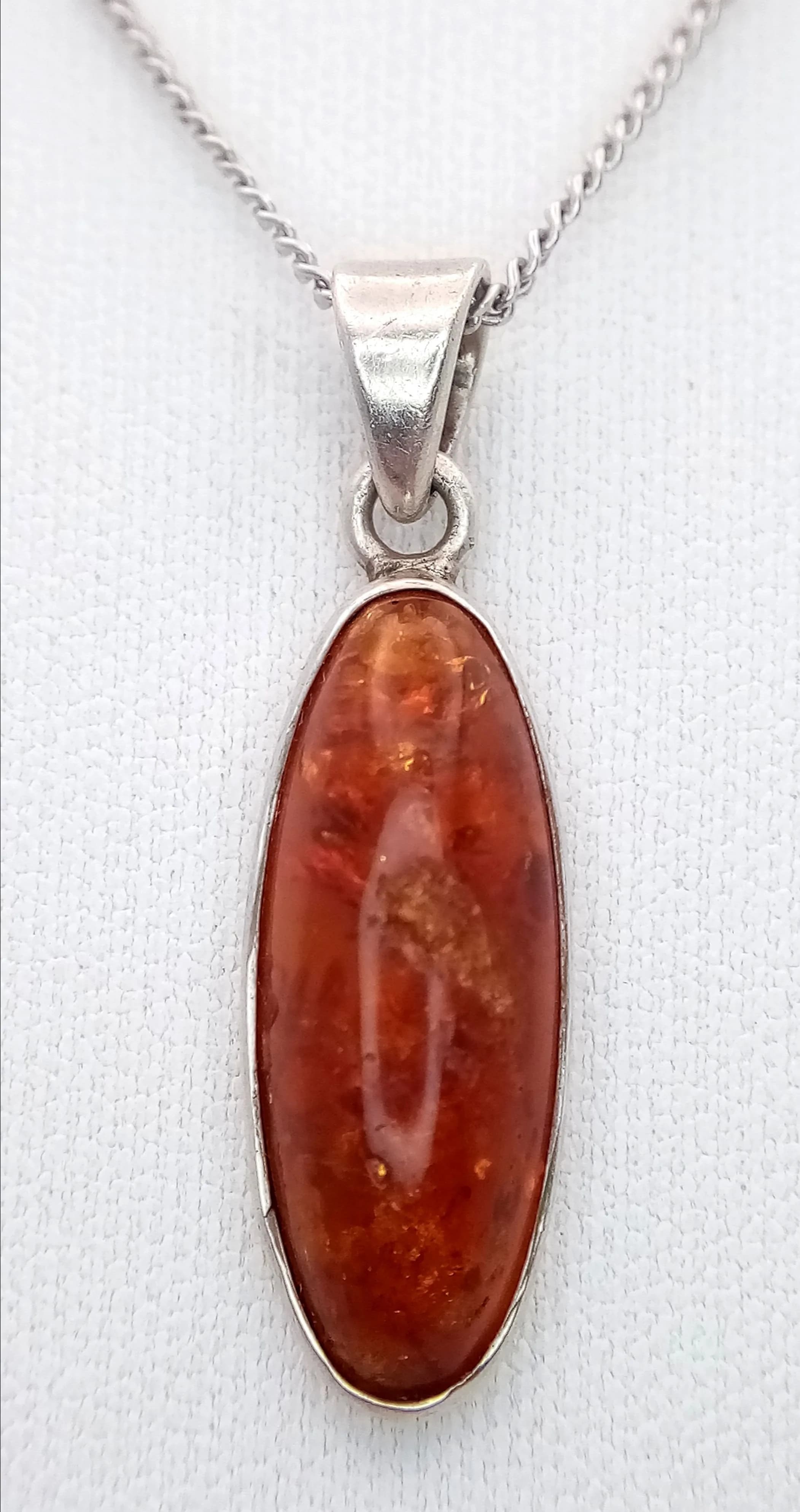 A Pretty 925 Silver Amber Cabochon Pendant Necklace - 44cm Length. Features an oval amber cabochon pendant suspended from a fine snake chain. The pendant measures 2.5cm x 1cm. Gross weight 5.13 grams.