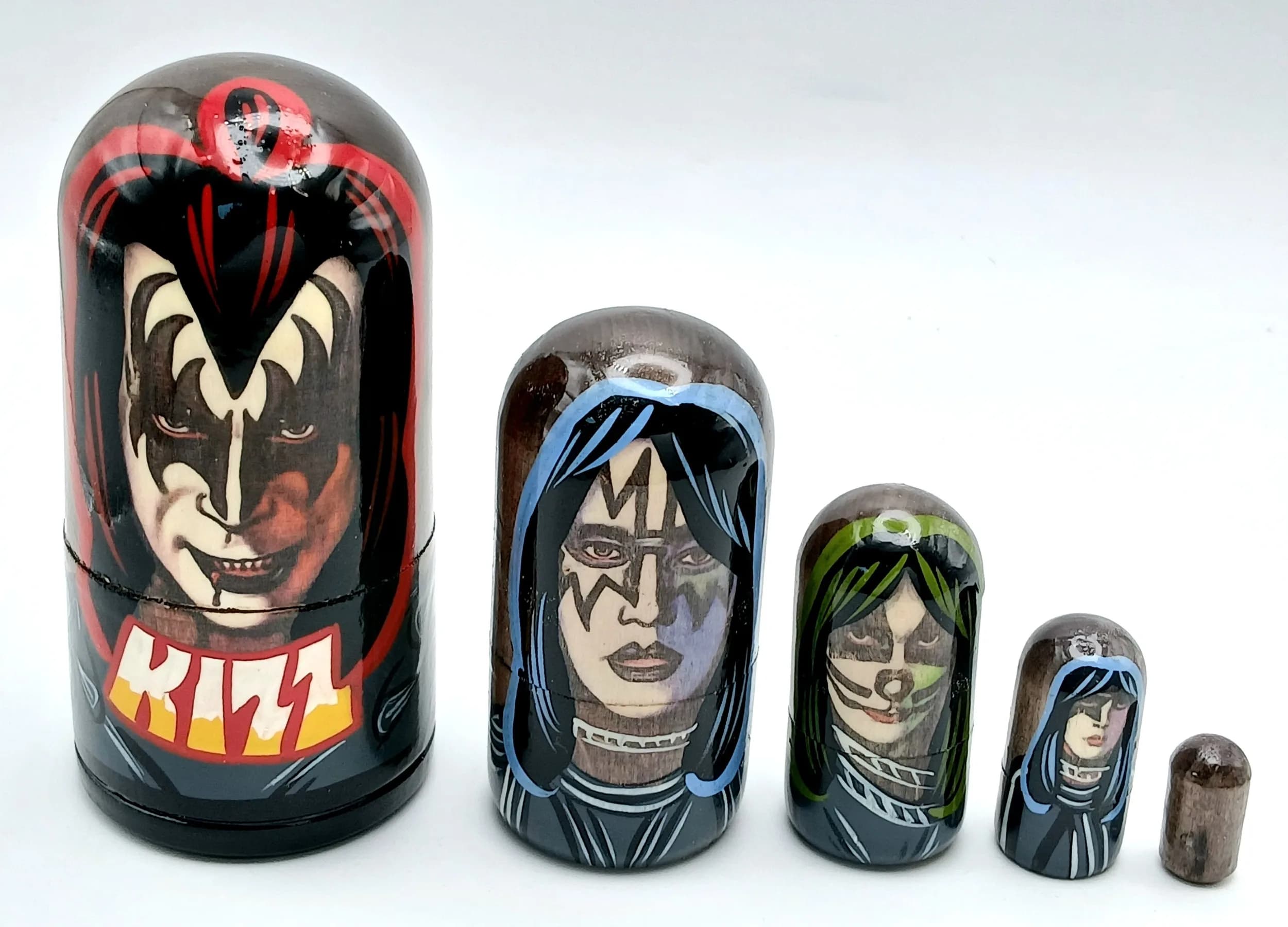 A KISS Style Russian Nesting Doll Set. Five-piece painted wooden nesting doll set featuring rock band-style figures. Made in Russia. Tallest doll measures 11cm. All dolls fit inside each other.