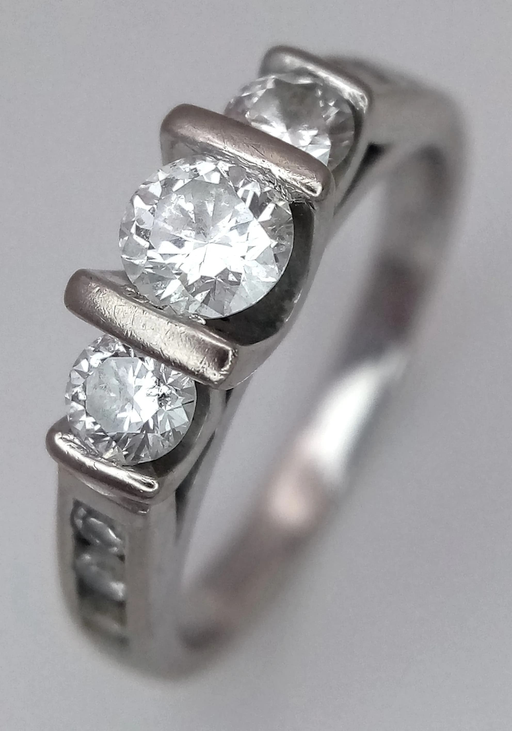 AN 18K WHITE GOLD 3 STONE DIAMOND RING PLUS 3 SMALL DIAMONDS ON EACH SHOULDER . 4.2gms size J/K