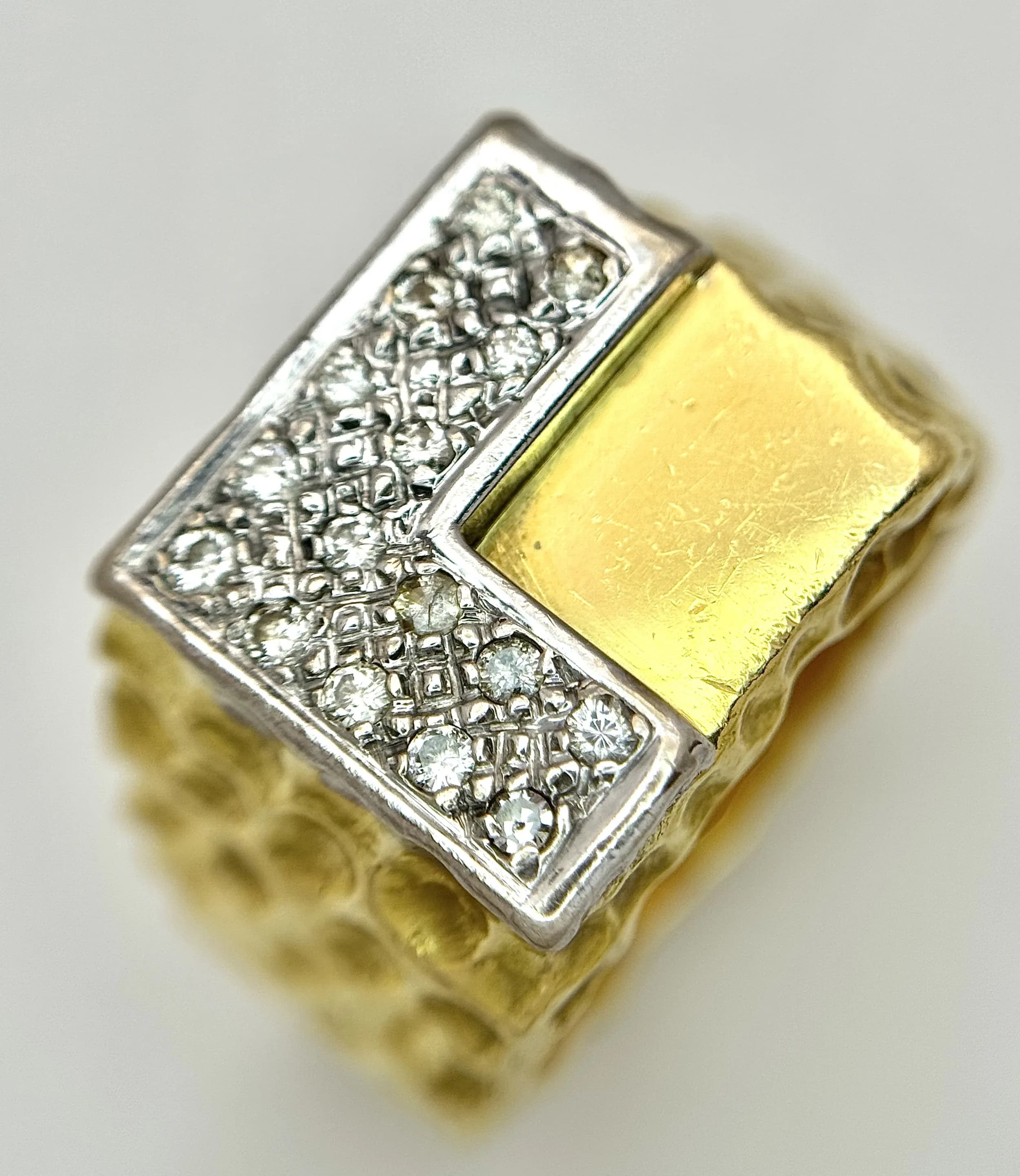 A Statement 18K Yellow Gold and Diamond Gents Signet Ring. Dimple effect band with an 'L' shaped diamond encrusted pave set face. Size X. 34.78g total weight.