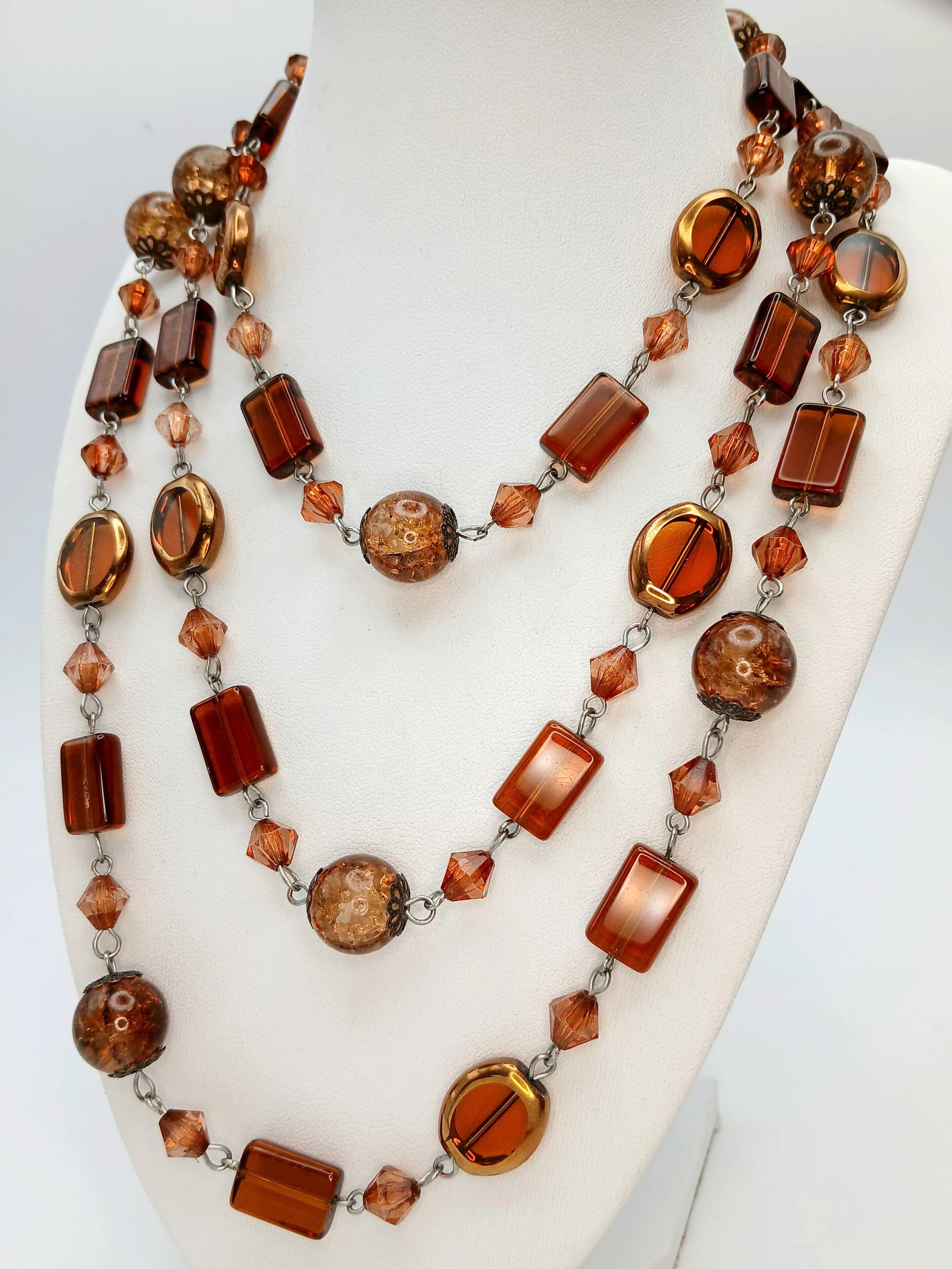 A Pretty Very Long Amber Bead Necklace. Features polished oval, round and cylindrical amber beads interspersed with faceted amber-tone crystal spacers. The necklace measures 138cm length.