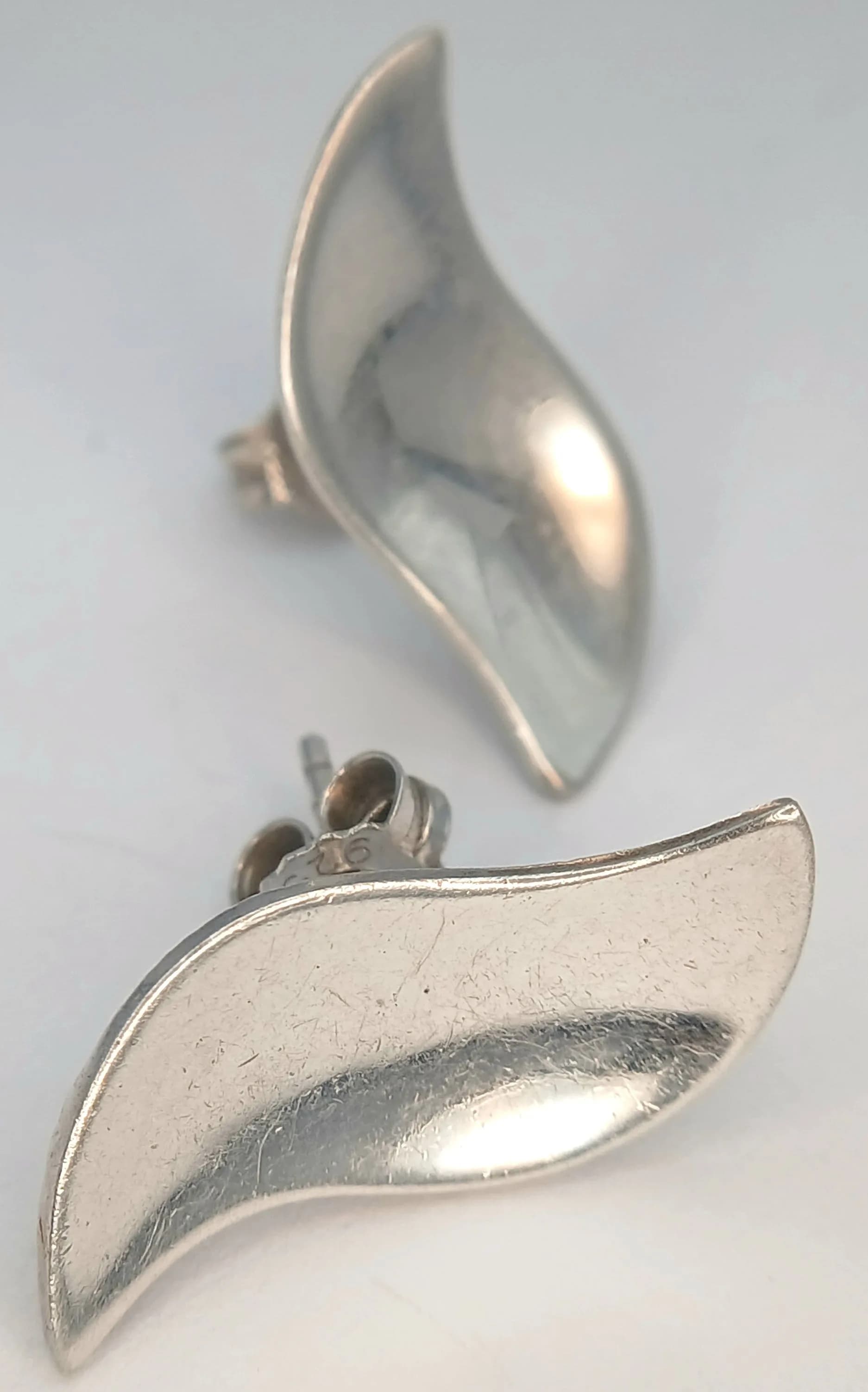 A Lovely Pair of 925 Sterling Silver Leaf Design Stud Earrings. Features a polished curved leaf design with butterfly back fittings. The earrings measure approx 2.4cm x 1cm. Gross weight 3.17 grams.
