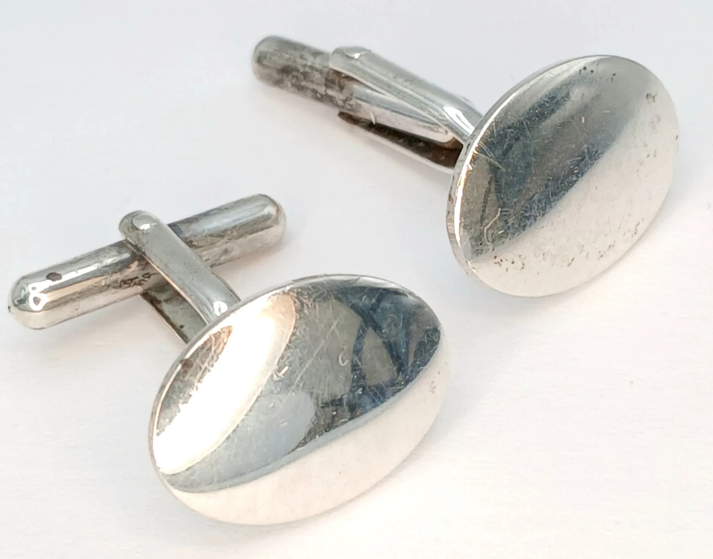 A Pretty Pair of Silver Oval Cufflinks. Features polished oval faces with swivel bar fittings. Each cufflink face measures 1.5cm x 1.1cm. Gross weight 4.41 grams.