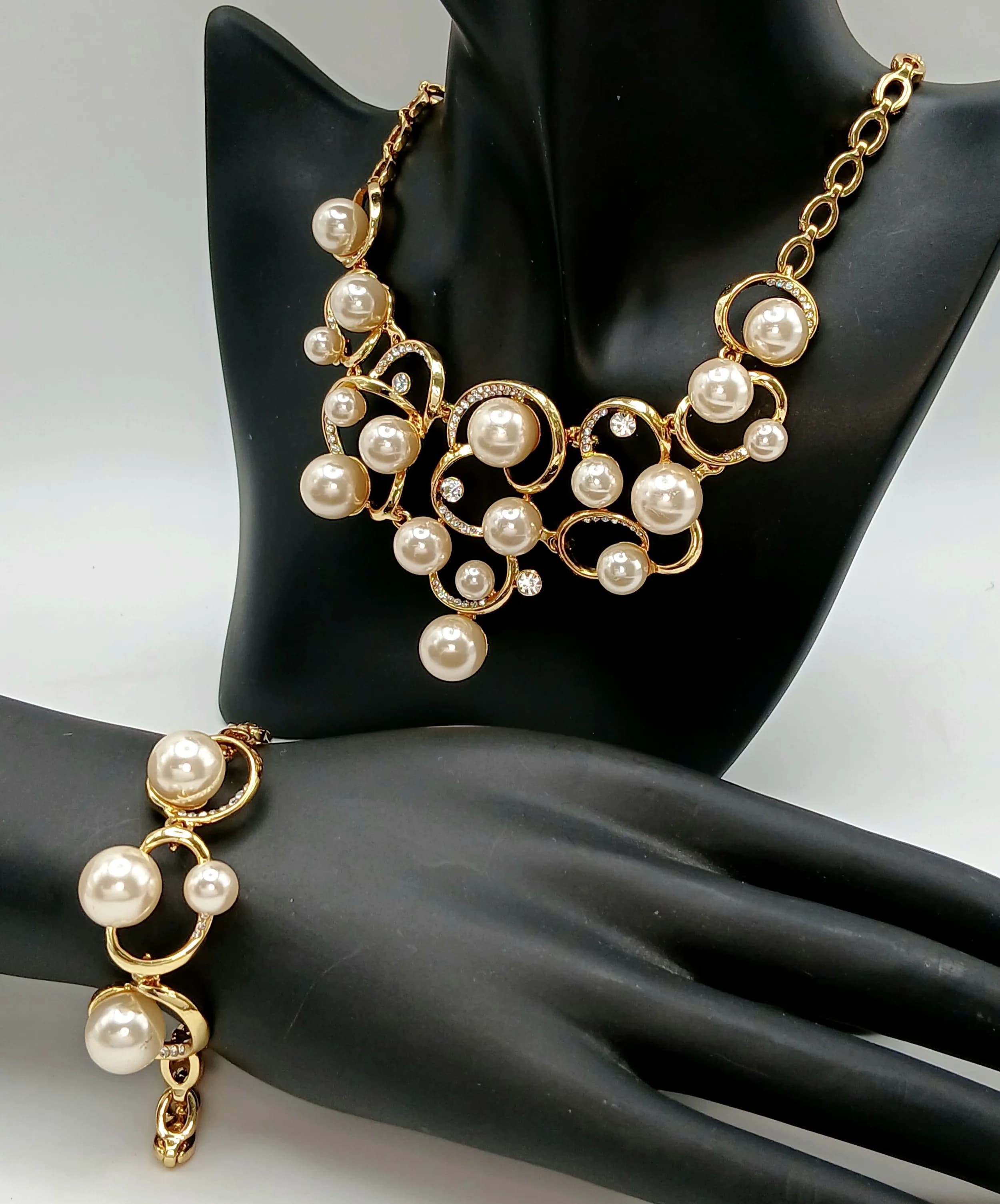 A Charming Lavaliere Gold Tone Faux Pearl and Crystal Set Necklace and Bracelet Set. The Necklace measures 34cm in length and features a decorative openwork pendant drop measuring 6cm x 10cm, set with faux pearls and clear crystal highlights. The matching Bracelet measures 22.5cm in length with similar faux pearl and openwork detail. Comes with a presentation box.