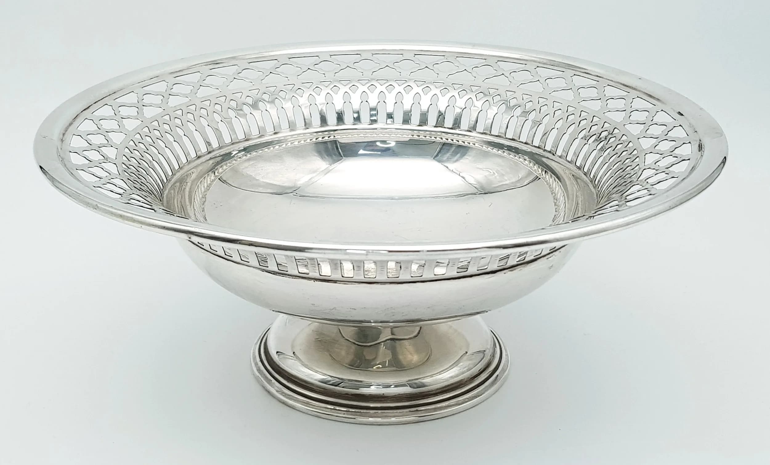 A SOLID SILVER PIERCED PEDESTAL BONBON DISH HALLMARKED BIRMINHAM 1927 HAVING INTRICATE PIERCED LATTICE WORK AROUND THE RIM . 322.4gms 22cms DIAMETER AT RIM