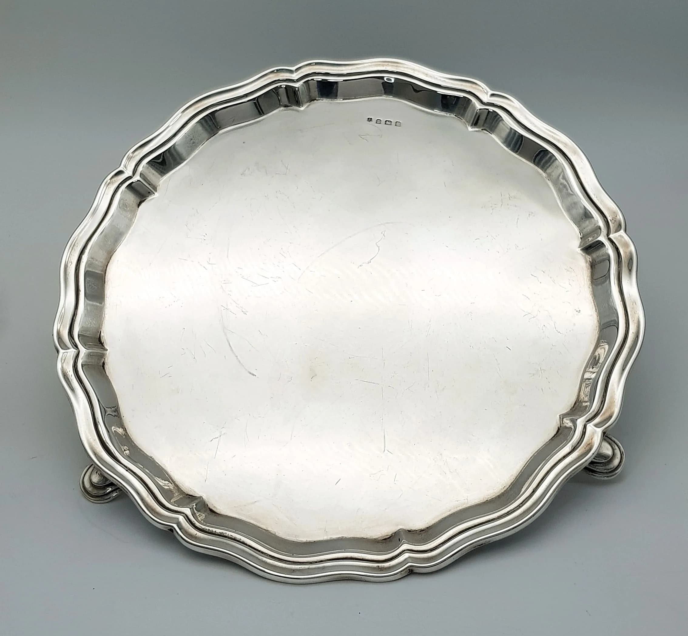 A SILVER FOOTED SALVER WITH SCALLOPED EDGE HALLMARKED BIRMINGHAM 1932 . 510gms 25cms DIAMETER