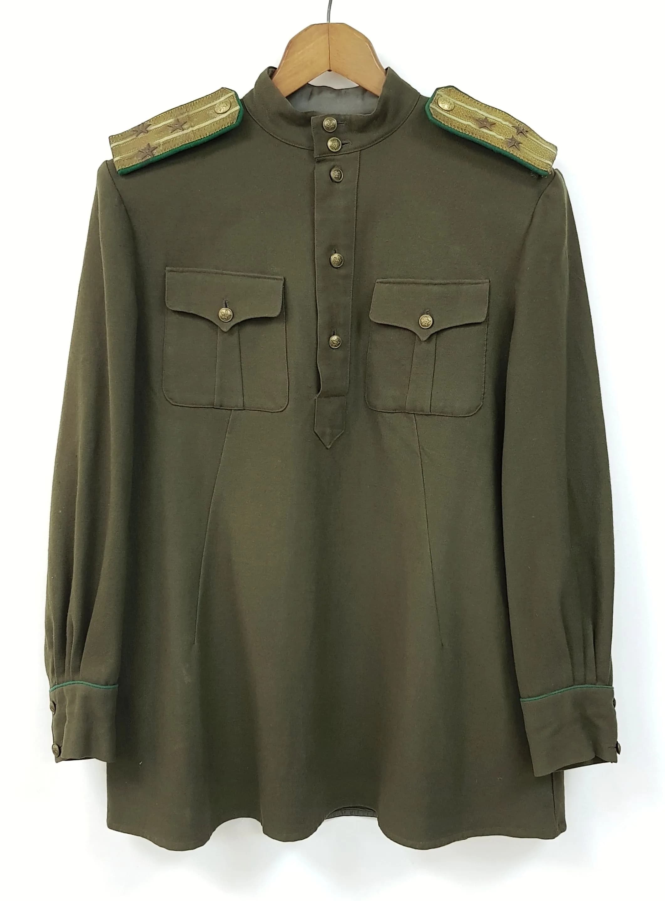 A Soviet Era Military Tunic - Possibly 1950/60s. Olive shade material with closed collar and two flapped breast pockets. Green edged shoulder boards with gilded background and rank stars (Possibly senior Lieutenant of Soviet Border Troop). 80cm length. Circa 106cm chest.