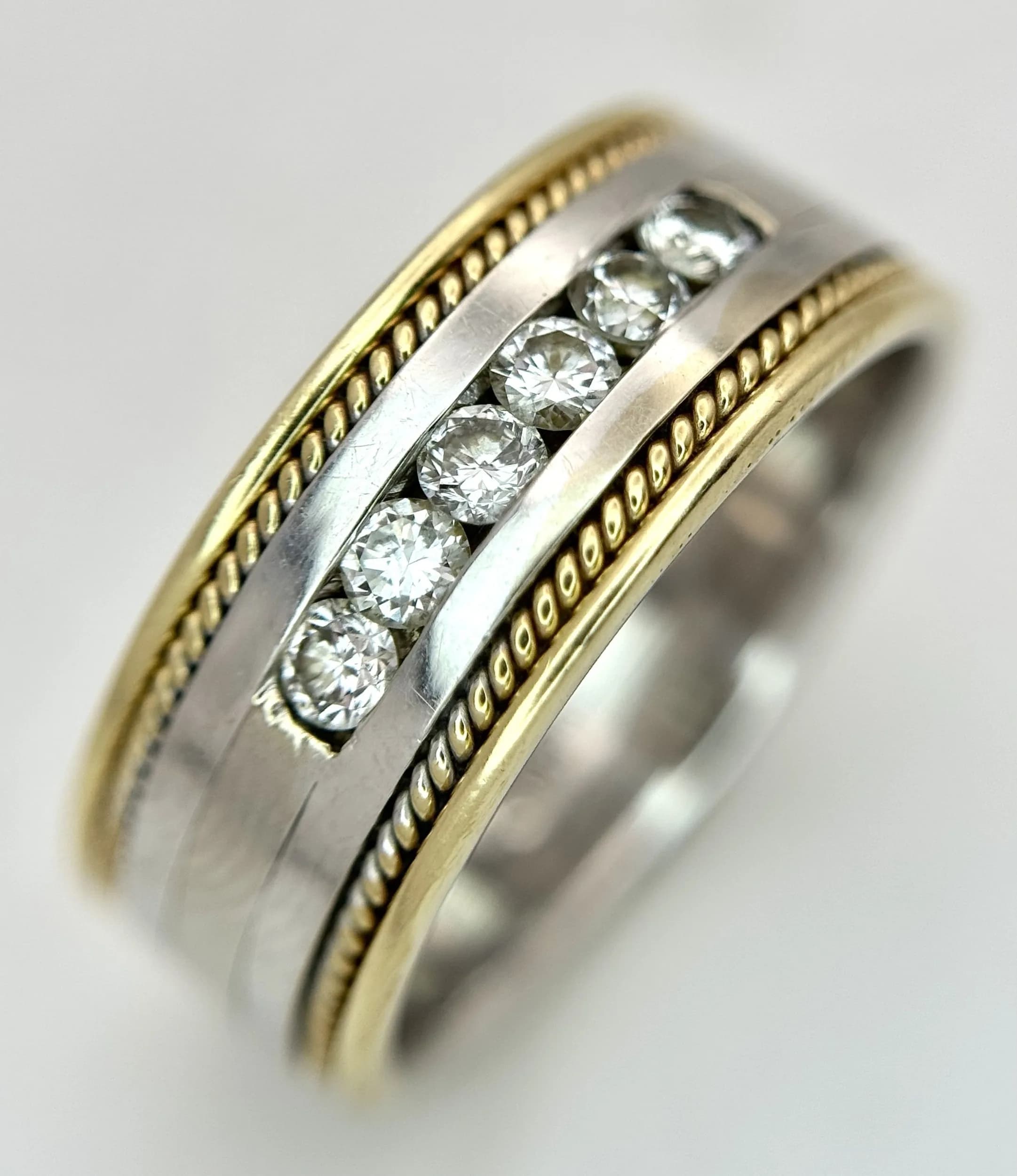 A 14K Yellow and White Gold Band Ring with Channel Set Diamonds. 0.30ctw of round brilliant cut diamonds having H colour and SI2 clarity. 9mm width. Size U. 9.56g total weight.