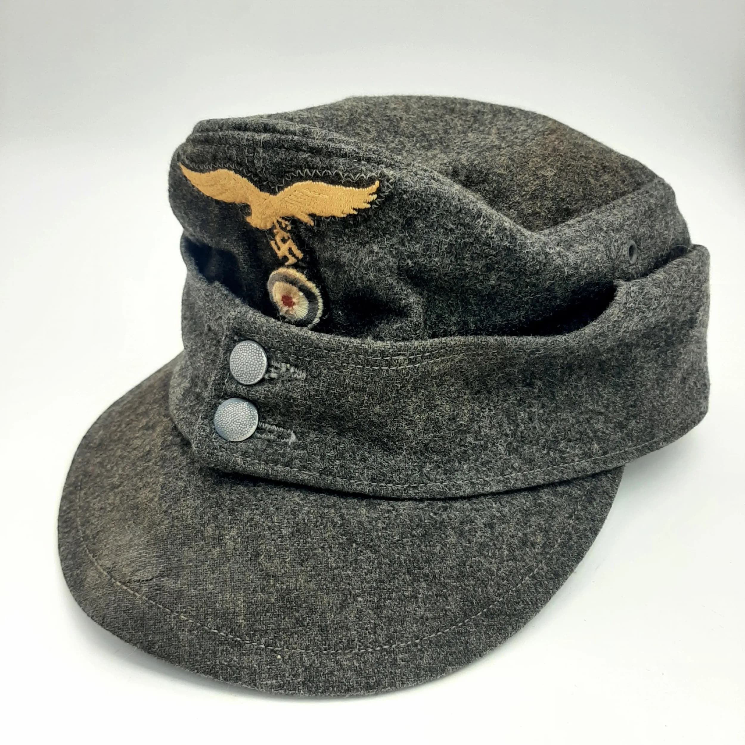 A WW2 German Luftwaffe M43 Field Cap. Dark blue grey wool with a two button closure and Eagle/Swastika Emblem. Markings on interior of R.B. NR.0/0639/0010. 1944. Size 60.
