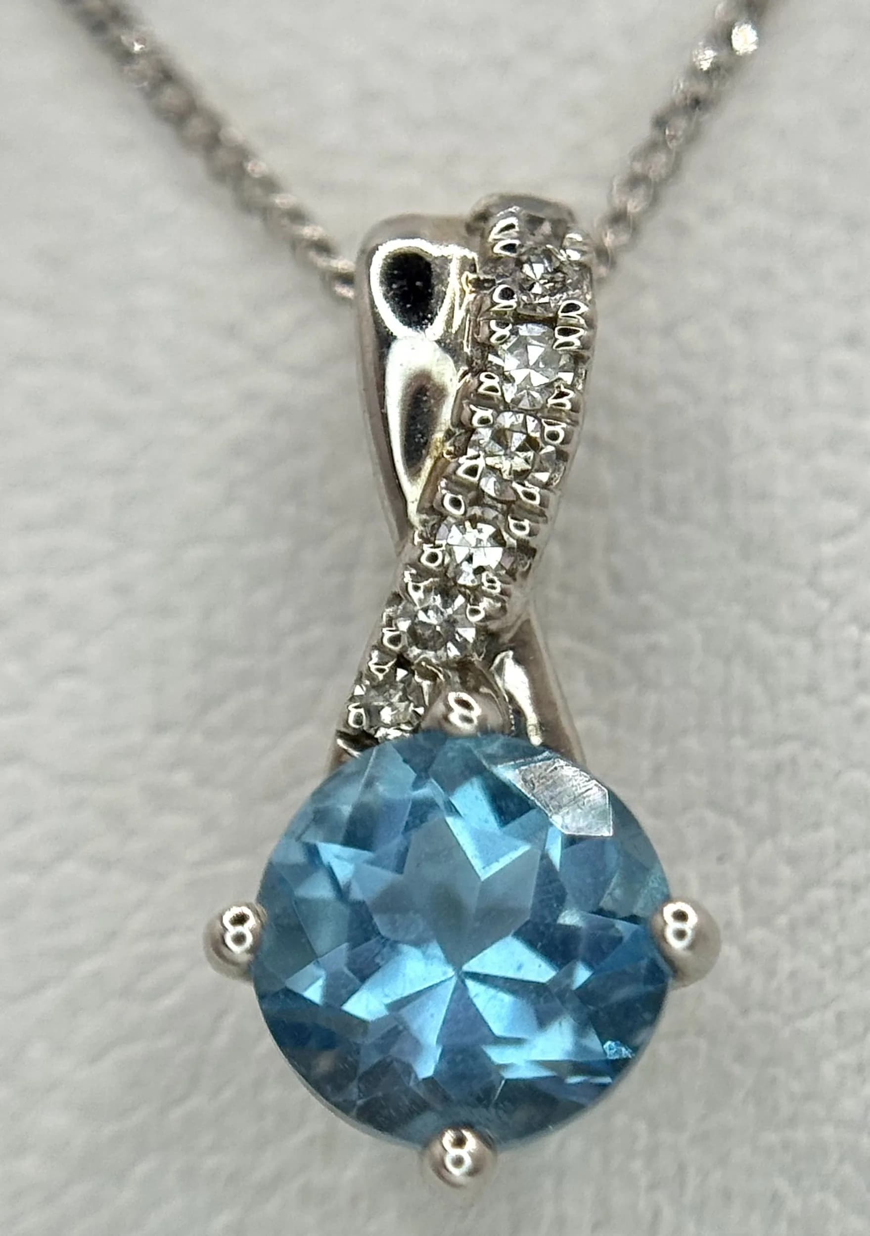 A 9K White Gold, Diamond and Topaz Crossover Pendant - On a 9K white gold chain. 15mm and 42cm. 1.9g total weight. Ref: 029643