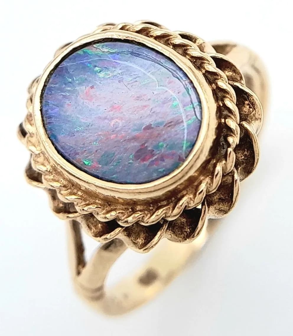 An Elegant Vintage 9k Yellow Gold, Hallmarked 1975, Opal Ring Size O. The Ring is set with a 10 x 8mm Oval Opal in a Rope Edge Mount. The Ring has a gross weight of 3.1 grams.