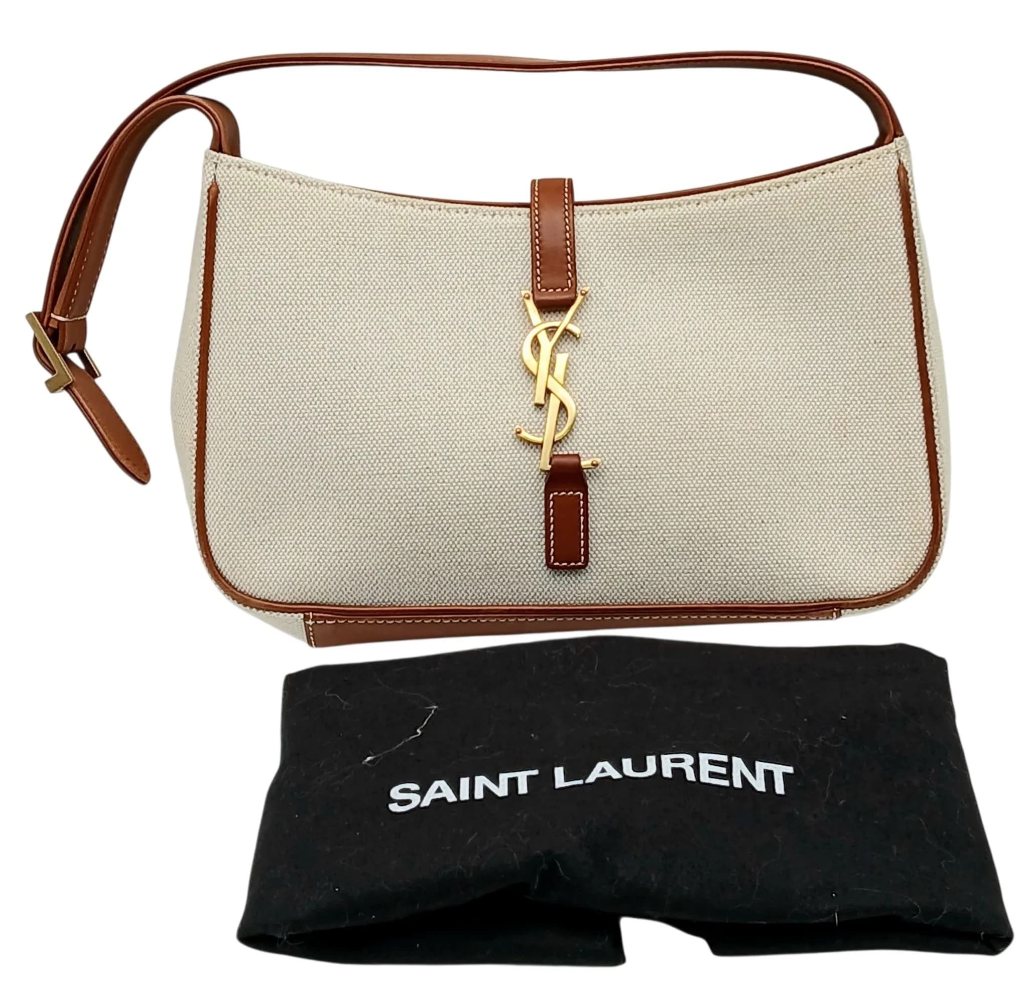 A Saint Laurent Le 5 à 7 Hand Bag. Beige canvas exterior with brown leather trim, gold-tone hardware and an adjustable brown leather shoulder strap. Gold-tone Cassandre YSL hook closure. Opens to a brown suede interior with one main compartment and a zipped inner side pocket. Approx. 24.3cm length x 15cm height x 5.5cm depth. Comes with dust cover bag. Stains to the interior - Please see photos or request a condition report. Ref: 29815.