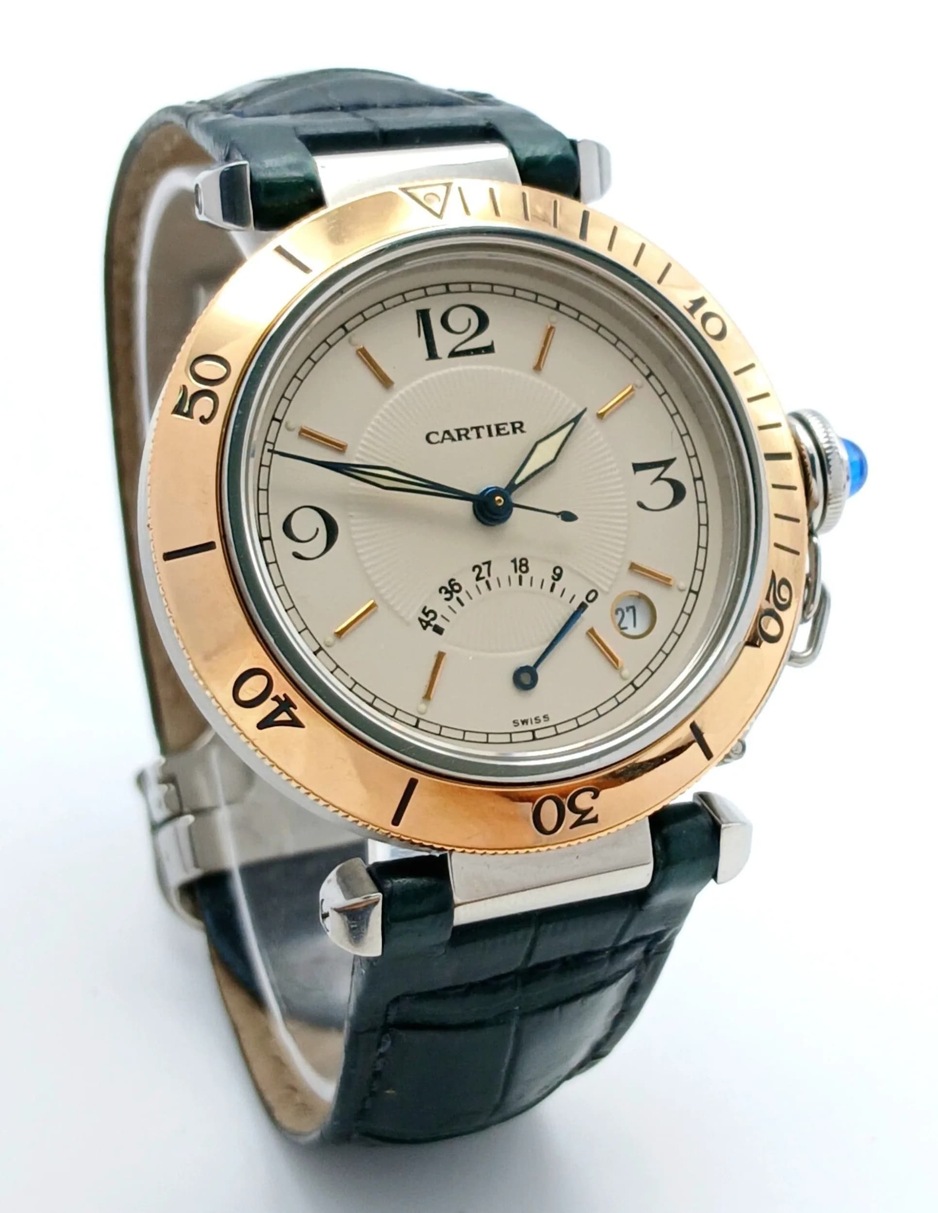 A Pasha de Cartier Automatic Gents Watch. Black leather Cartier strap with fold-over clasp. Stainless steel case with gold rotating bezel. Case - 38mm. Cream textured dial with power reserve sub dial and date window. Blue sapphire tipped crown. In working order.