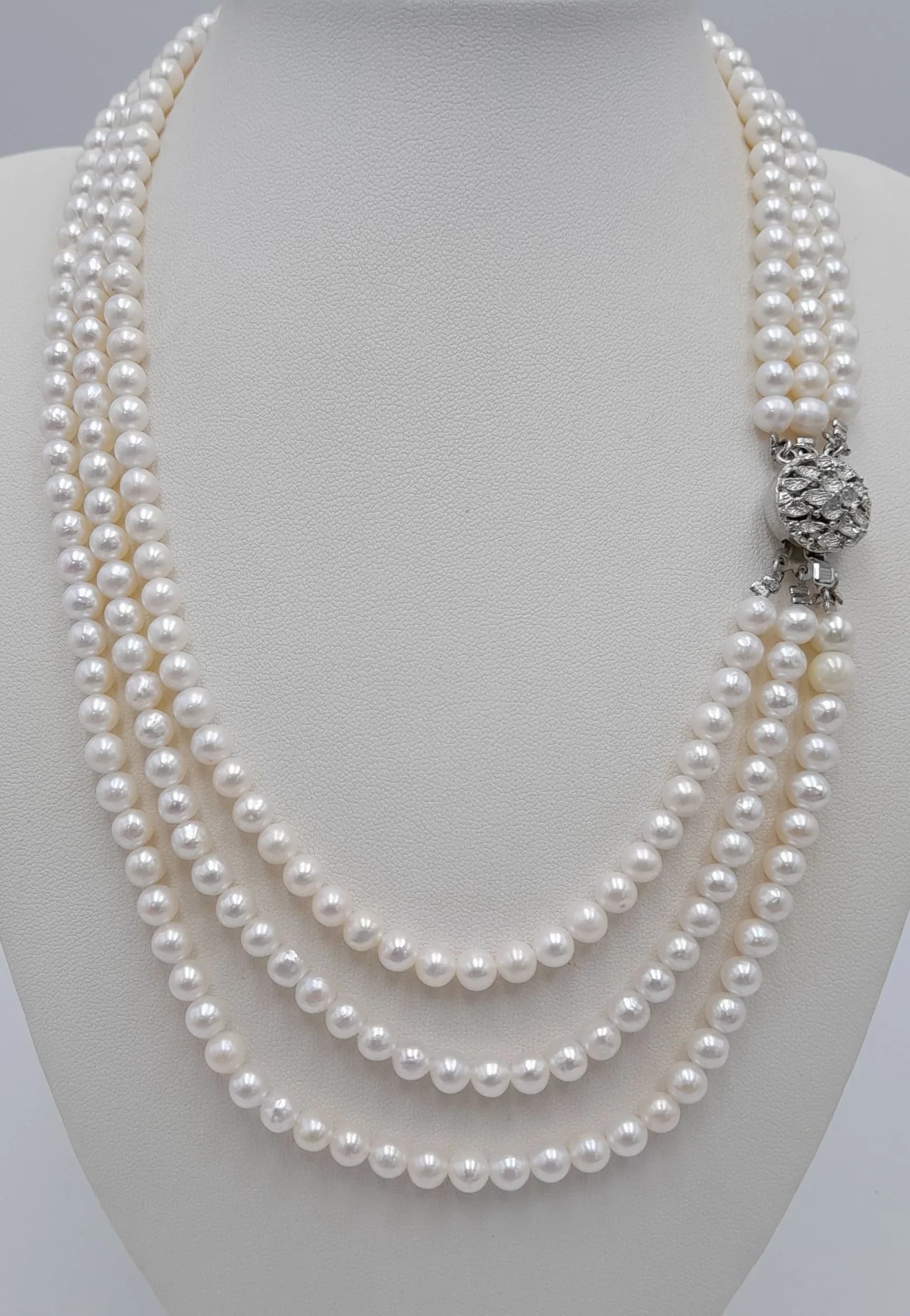 An eye-catching Triple Strand freshwater Pearl statement Necklace, with a decorative silver tone foliate clasp. Approx. 44cm length. Please see photos or request a condition report.