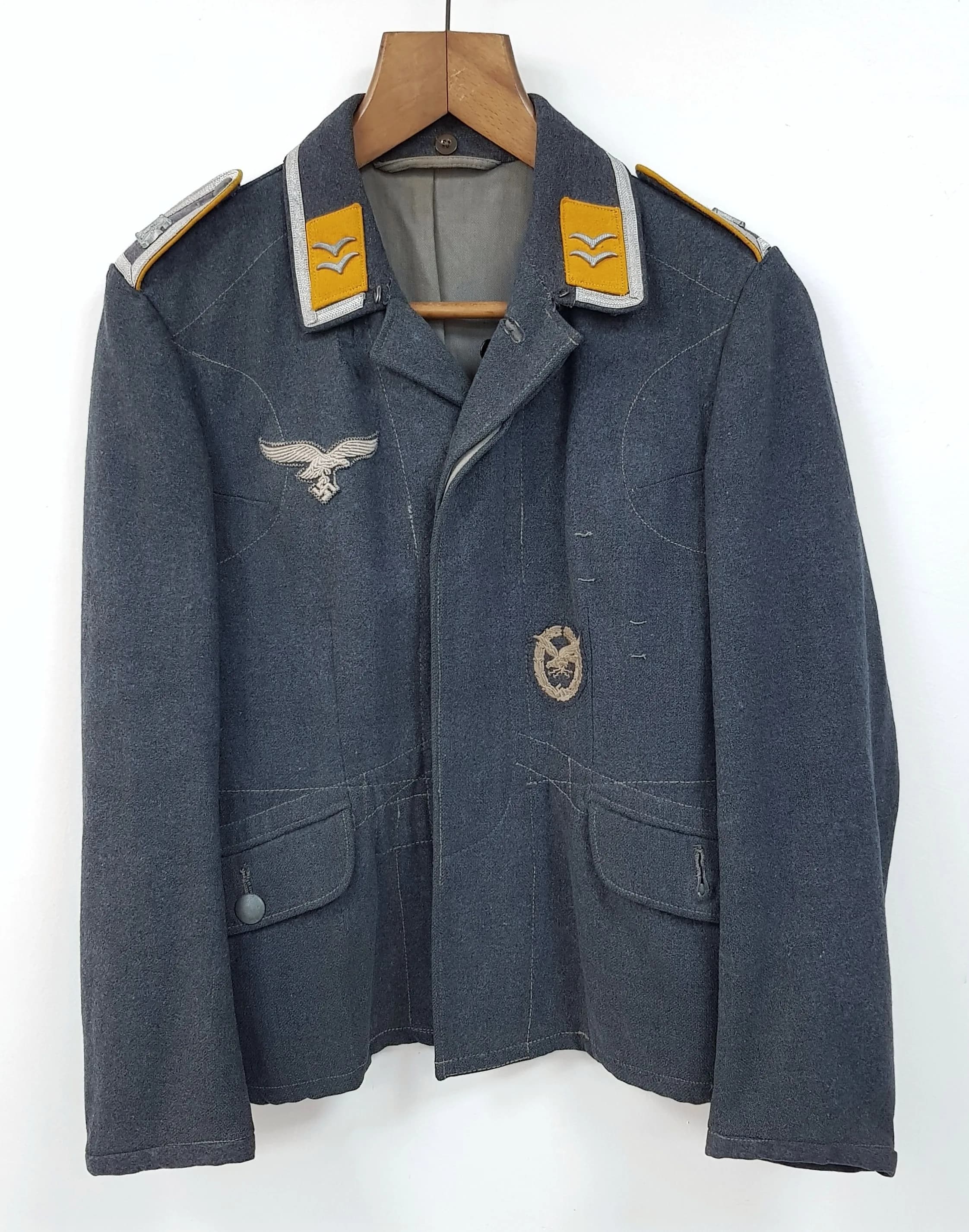 A Genuine WW2 Era Luftwaffe Service Tunic Specifically For Flying Personnel. Blue and grey wool with Gold collar tabs - branch colour for flying troops and aircrew. Two silver gull emblems, probably NCO rank - Silver tone cord along the collar edge. Breast eagle and Luftwaffe pilots badges. Interior of grey/blue lining with ink stamps: Makers name faded, size numbers - 41, 42, 90, 63,61.