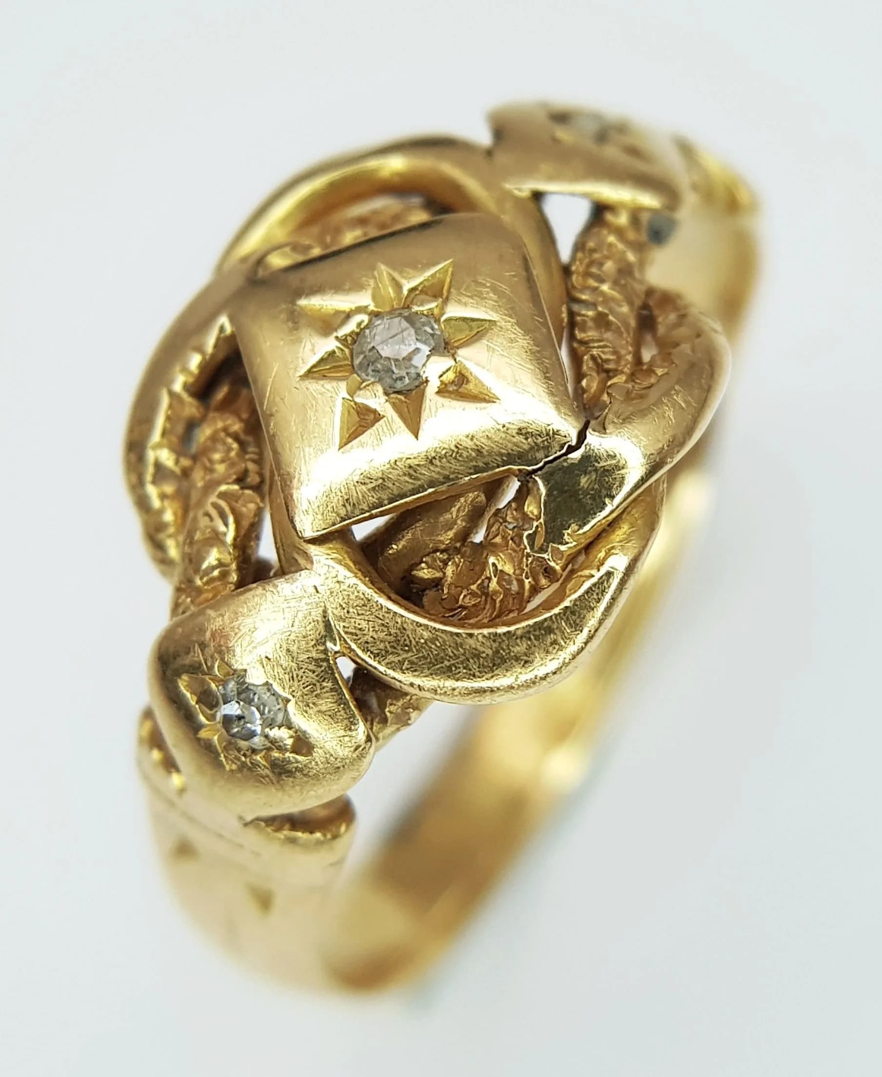 An Antique 18K Gold and Diamond Lover's Knot Ring. Features three star set old cut diamonds. Size R 1/2. 5.25g total weight.