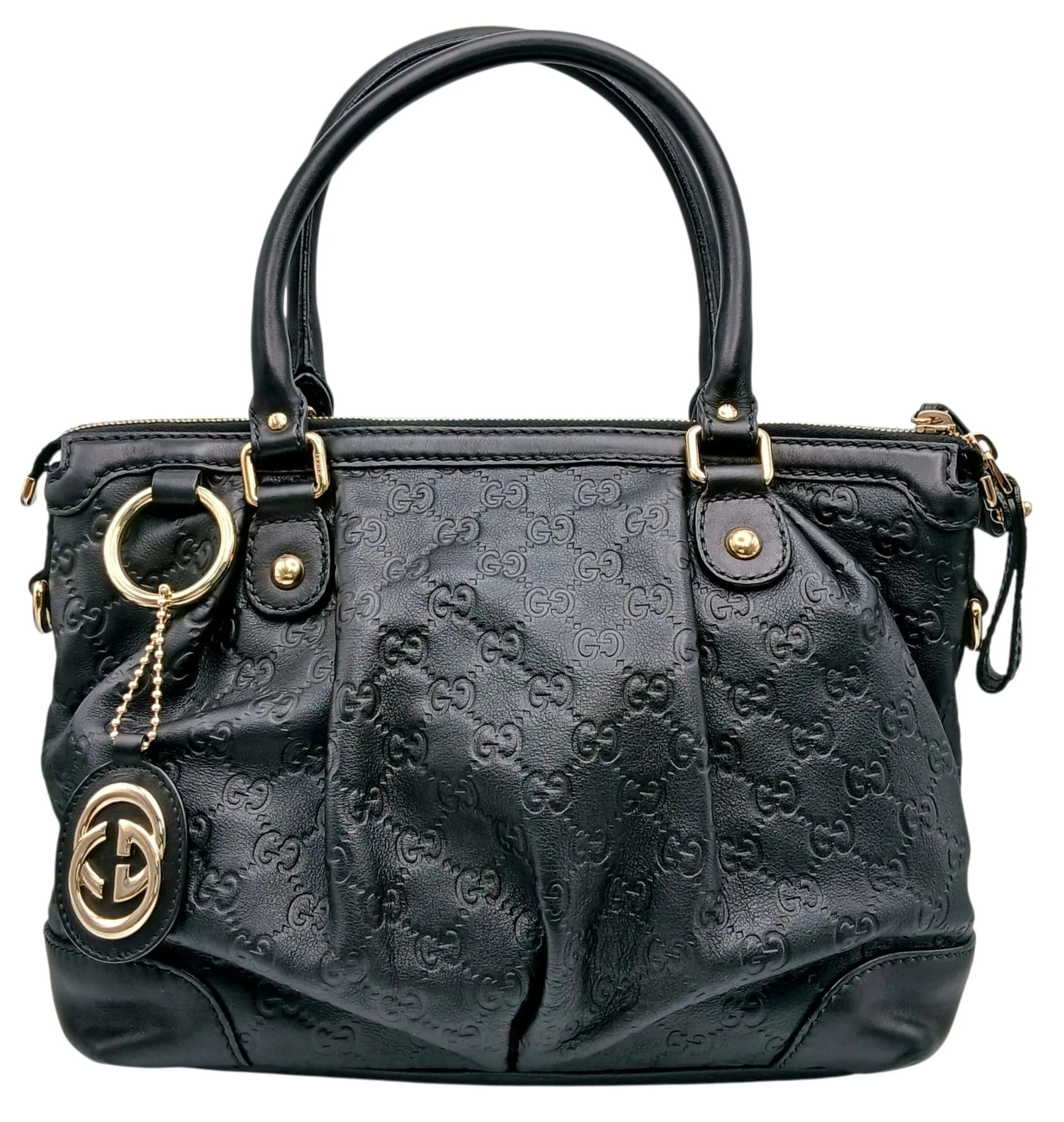 A Gucci Guccissima Sukey Handbag. Black GG monogram embossed leather exterior with silver-tone hardware, rolled leather top handles, detachable Gucci charm and zipped top closure. Beige fabric interior with a zipped inner side pocket and two open inner side pockets. Size approx: 32cm length x 23.5cm height. In good condition overall but Please see photos for details or request a condition report. Ref: 27506