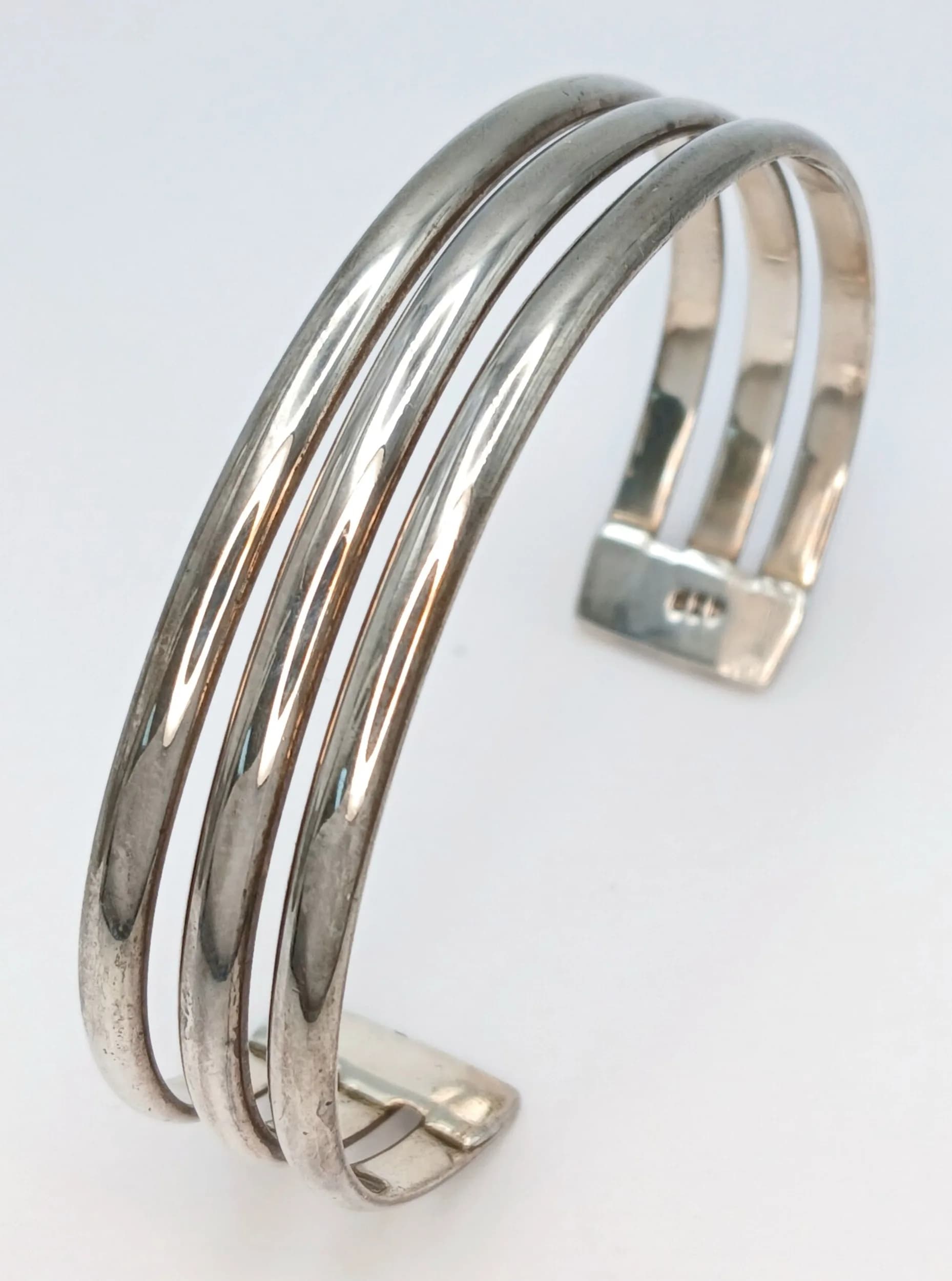 A 925 Silver Multi-Band Cuff Bangle. Polished openwork multi-band design with triple bar detailing. Hallmarked 925. Total weight 24.36 grams.