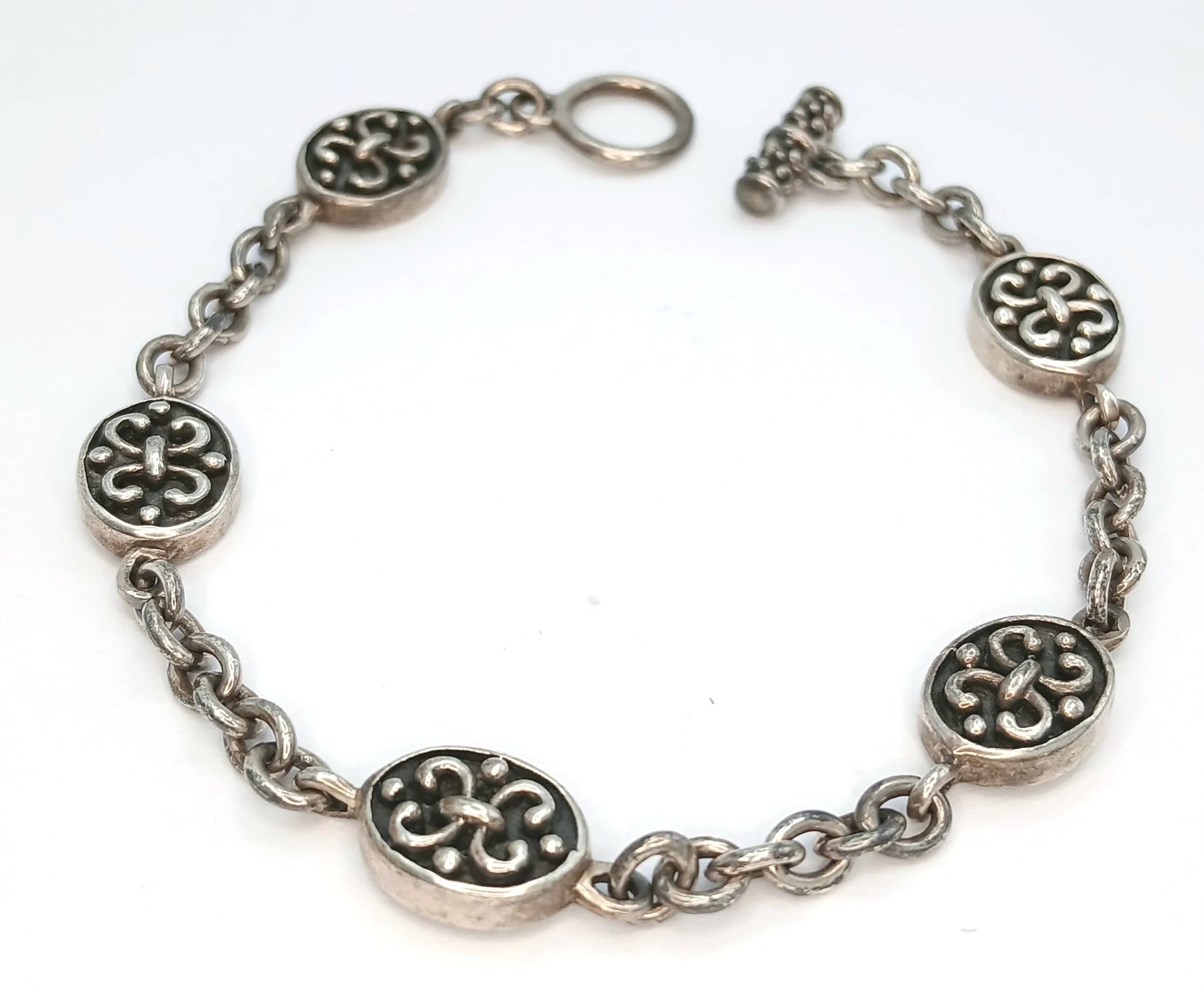 A 925 Silver Disc Link Bracelet. Alternating chain links with decorative oval disc panels with Celtic-style motifs. Hallmarked 925. Approx 20cm length. Total weight 14.83 grams.
