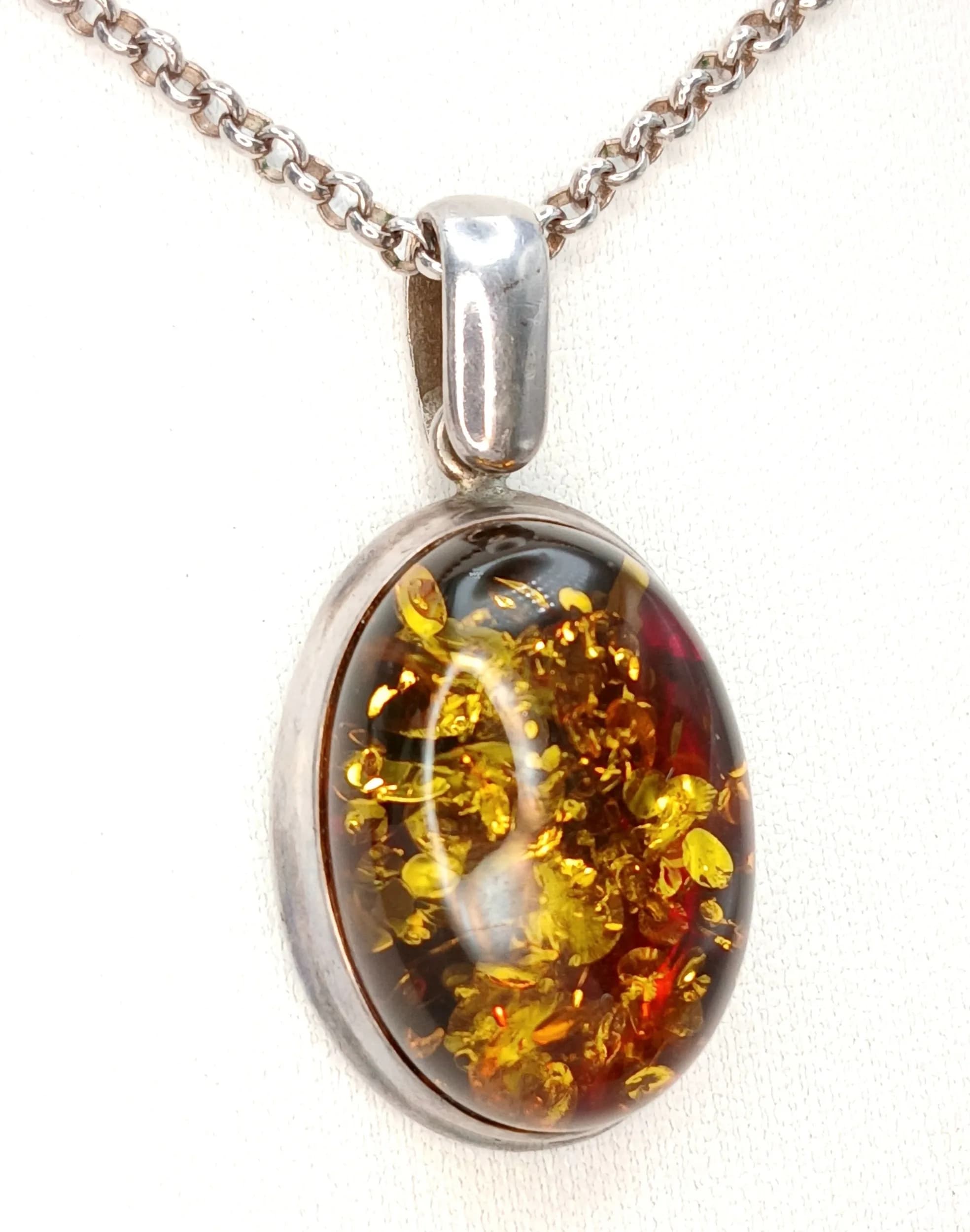 A 925 Silver Amber Pendant Necklace. Oval amber pendant set in a silver mount on a 72cm belcher chain. Pendant measures 4cm drop. Hallmarked 925. Total weight 22.71 grams.