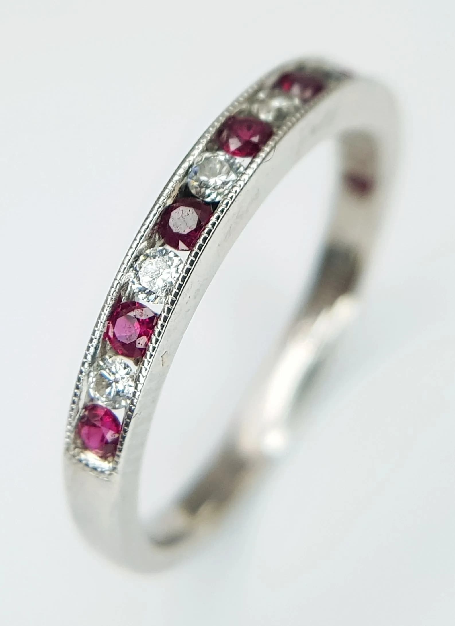 AN 18K WHITE GOLD, DIAMOND AND RUBY SET, HALF ETERNITY RING. 2.1G, SIZE K. SC 7073