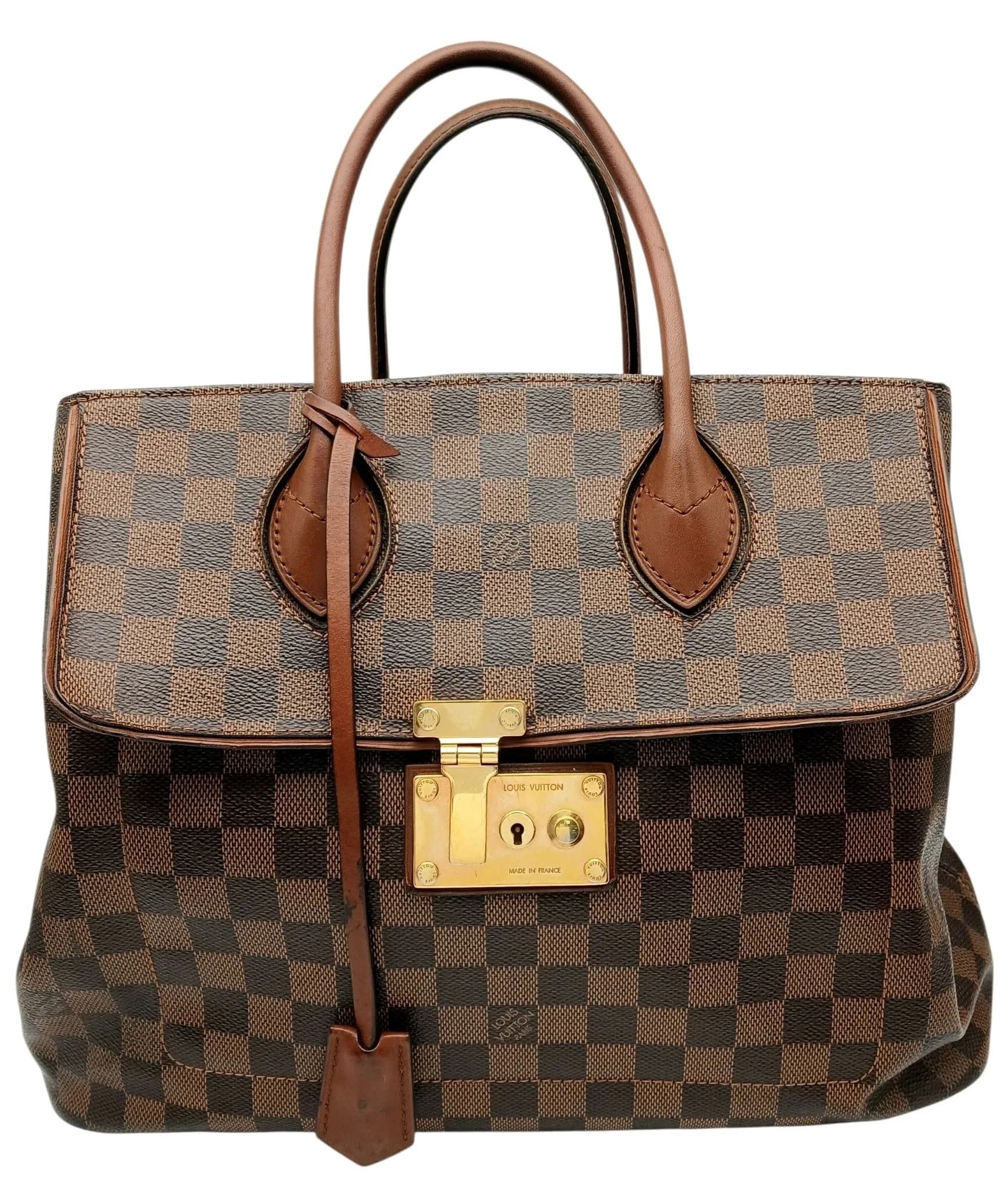 A Louis Vuitton Damier Ebene Ascot Bag. Brown Damier Ebene coated canvas exterior with brown leather trim, gold-tone hardware, double rolled leather top handles, front flap pocket with S-lock closure, clochette with keys and four protective base studs. Open top opens to a burgundy suede interior with three main compartments, including a central zipped compartment, one zipped inner side pocket and three open inner side pockets. Approx. 36cm length x 28.5cm height. Light marks and wear to the leather trim, with scratches and tarnishing to the hardware - Please see photos or request a condition report. Ref: 29802.