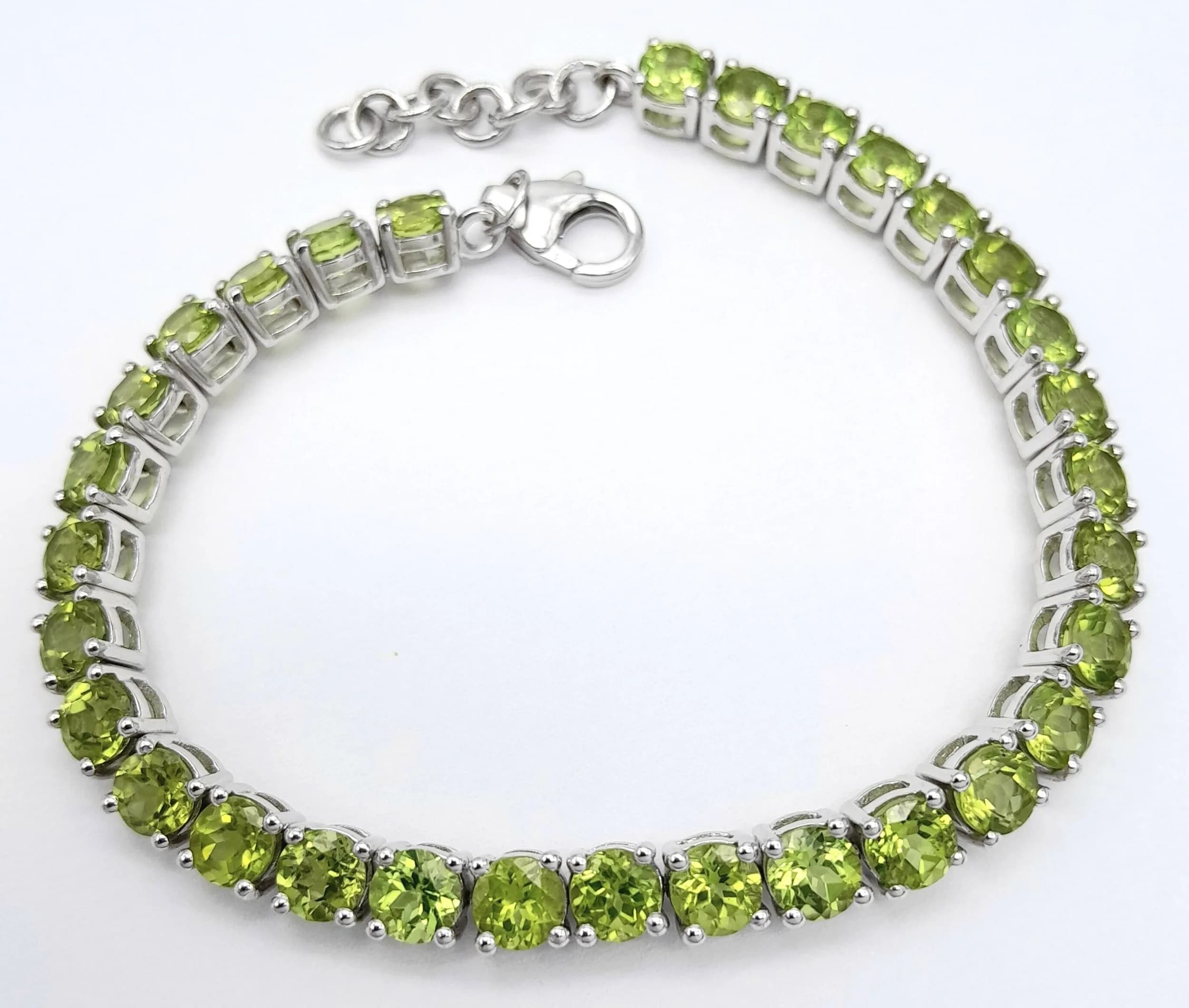 A Stylish Sterling Silver Peridot Set Tennis Bracelet-Fit 19 to 21cm. Set with Thirty-One 5mm Round Cut Peridot, approximately 15.5 carat. Gross weight 18.4 grams.