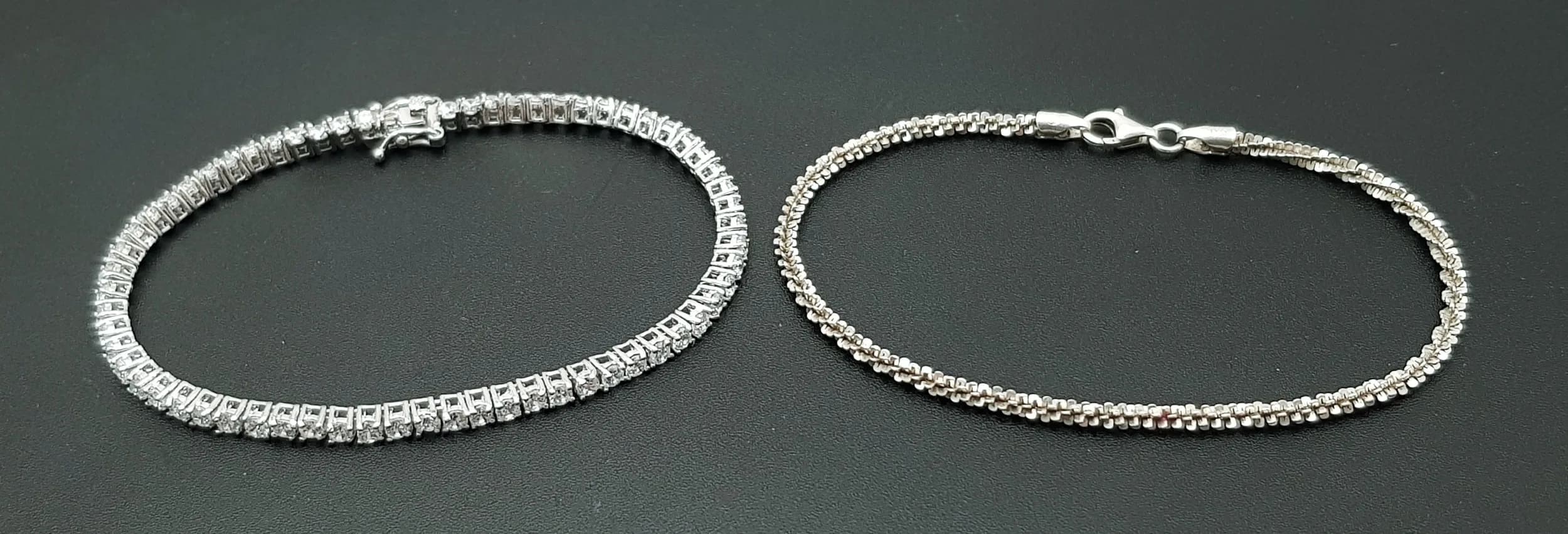 A Parcel of Two Sterling Silver Bracelets. Comprising 1) A 19cm Length Cubic Zirconia Tennis Bracelet-3mm wide and weighing 8.32 grams and 2) A Zip Chain Link Sterling Silver Bracelet-19cm Length. The Bracelet weighs 3.24 grams.