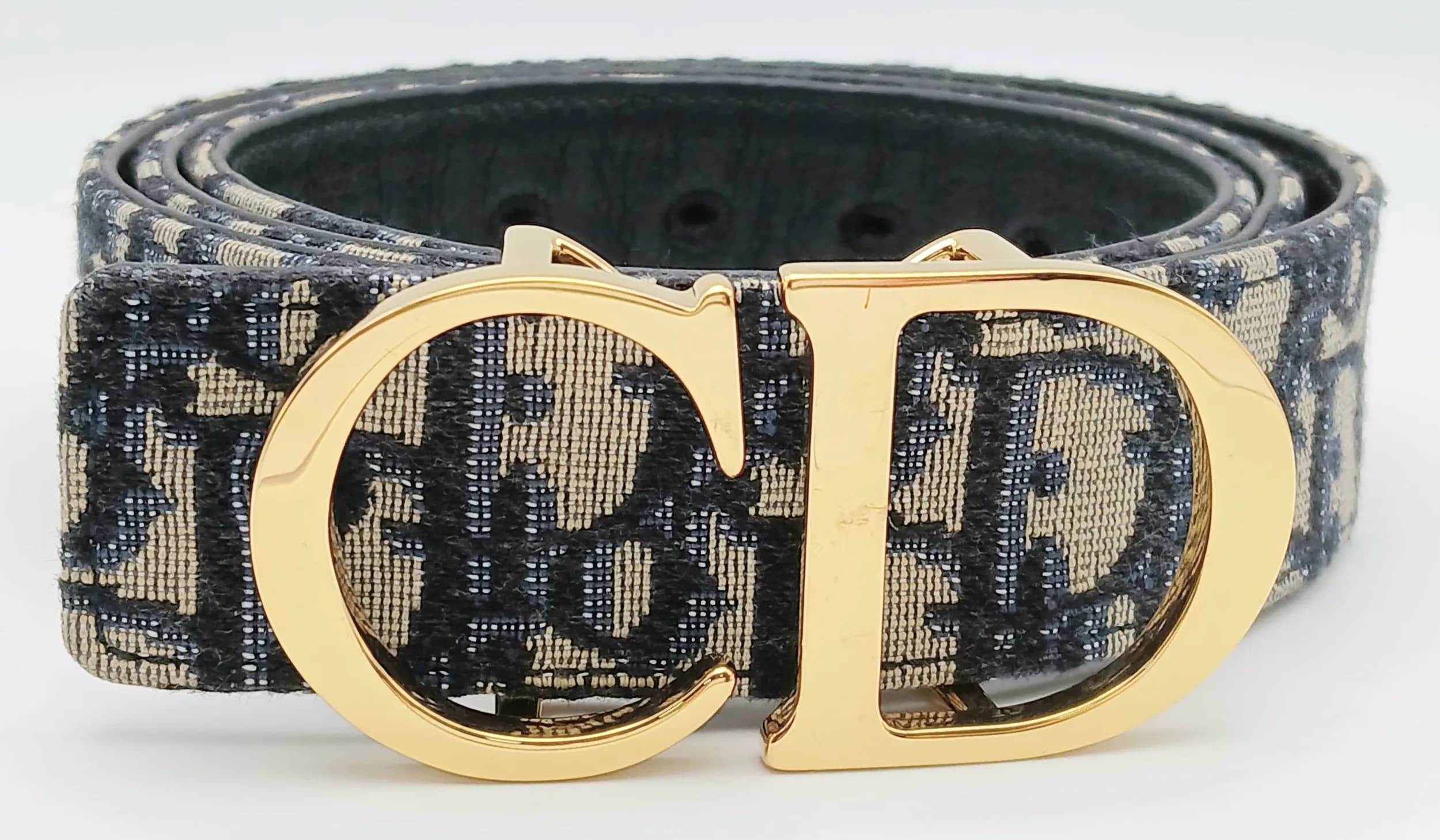 A Christian Dior 30 Montaigne Reversible Belt. Crafted in blue and beige Dior Oblique jacquard canvas with a black smooth leather reverse, finished with a large gold-tone CD initials buckle. Adjustable fastening with multiple holes. Approx. 117cm x 3.5cm. Comes with a dust cover bag, tag and box. Please see photos for condition. Ref: 29617.