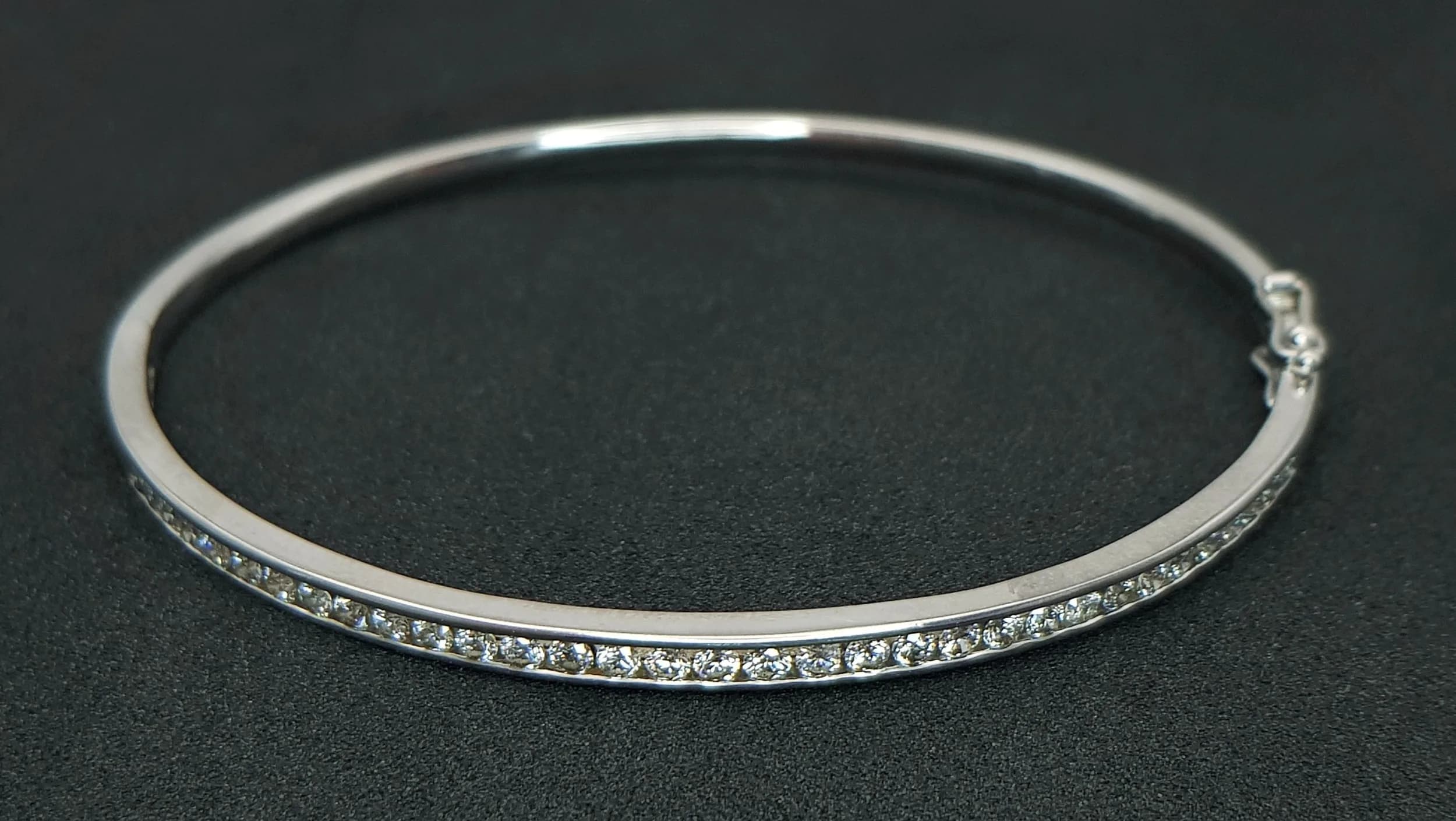 AN 18K WHITE GOLD, DIAMOND SET BANGLE. 1.00CTW DIAMONDS. 6CM INNER DIAMETER. 11.2G. SC 7087