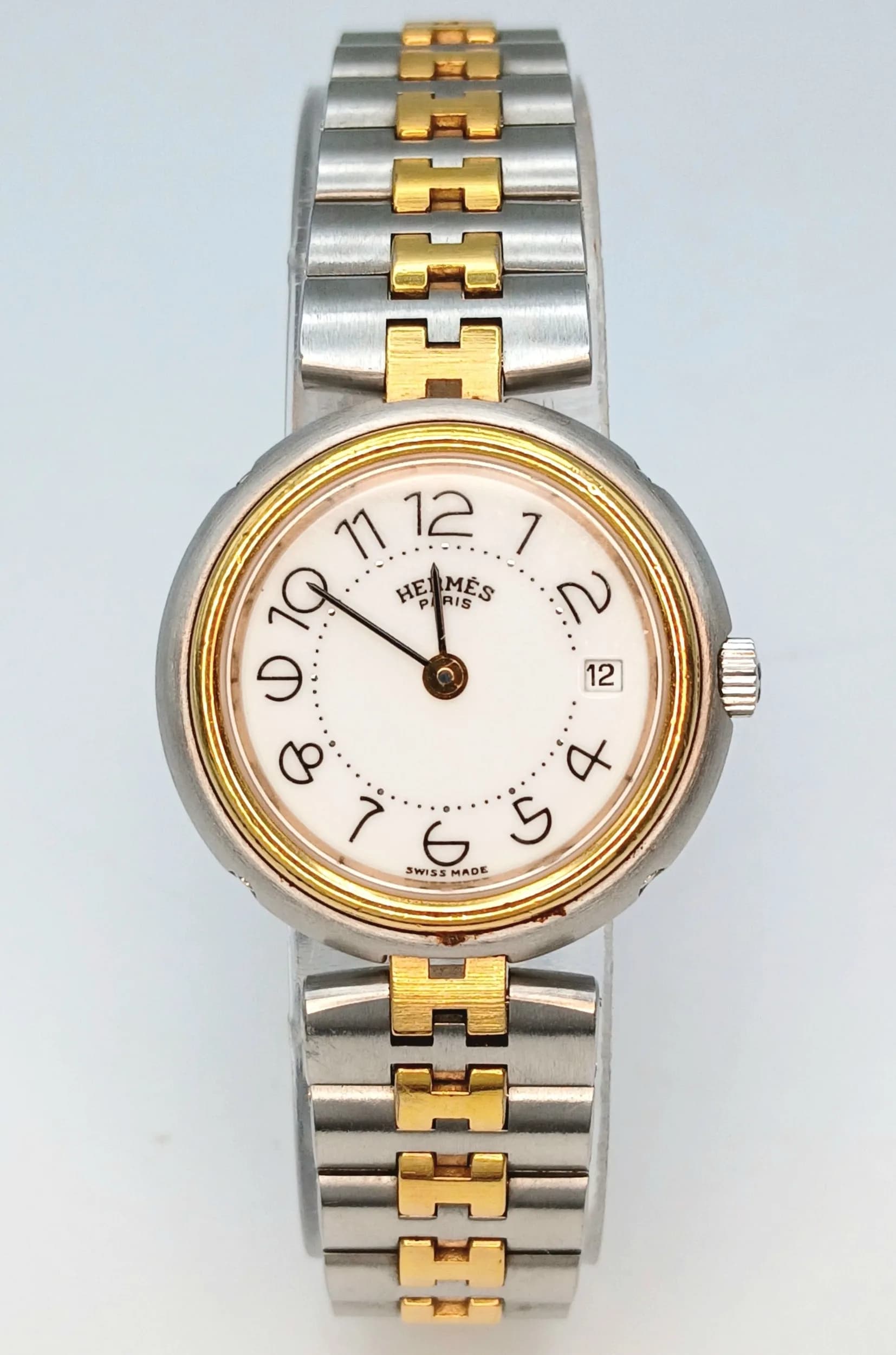 An Hermes Profile Two Tone Quartz Ladies Watch. Gilded H stainless steel bracelet. Two tone stainless steel case - 26mm. White dial with date window.