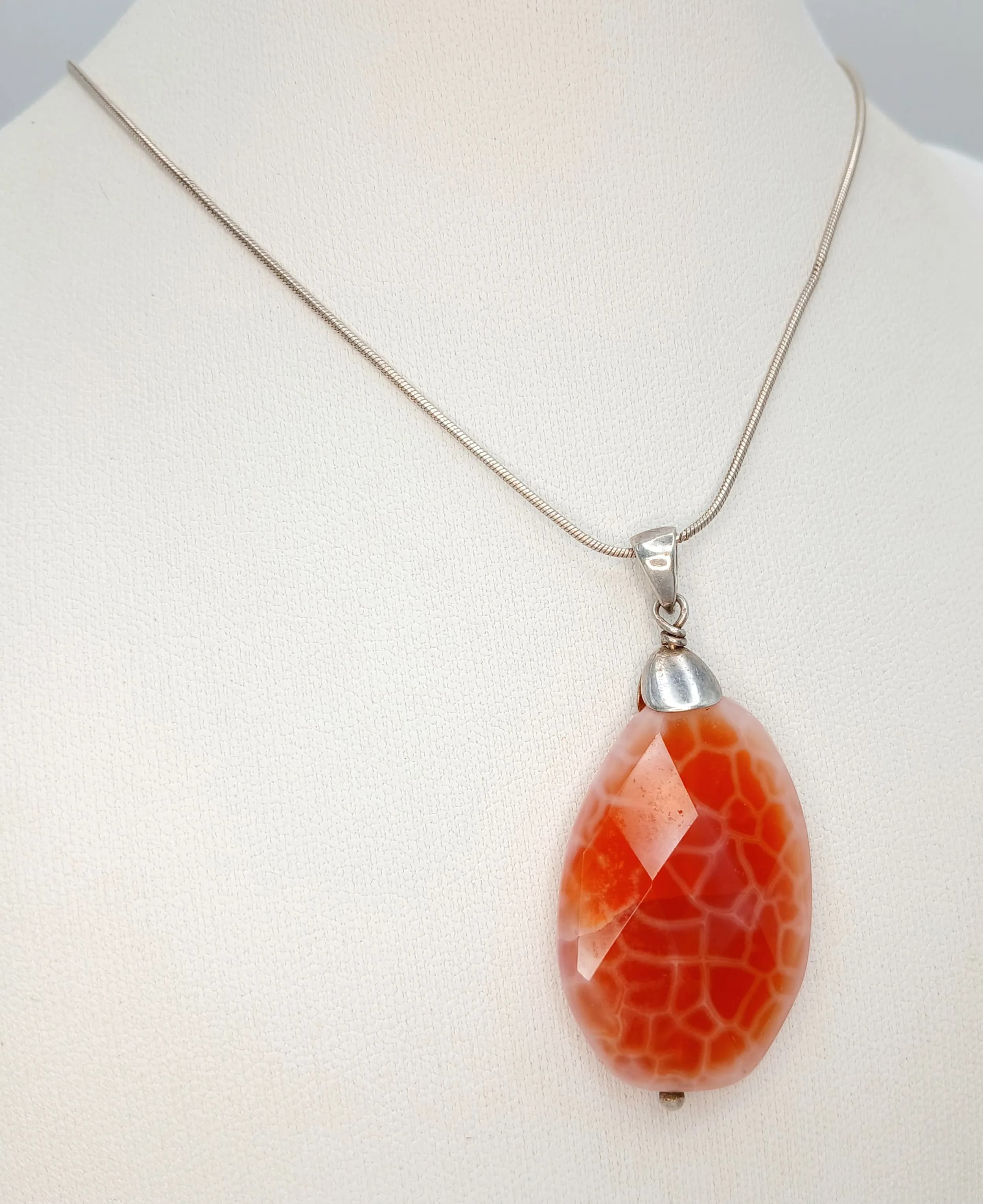 A Striking 925 Sterling Silver Red Agate Pendant Necklace – 44cm Length. The pendant is set with a large faceted teardrop-shaped red agate with a distinctive crackle pattern. The pendant measures 4cm x 2.5cm. Gross weight 11.75 grams.