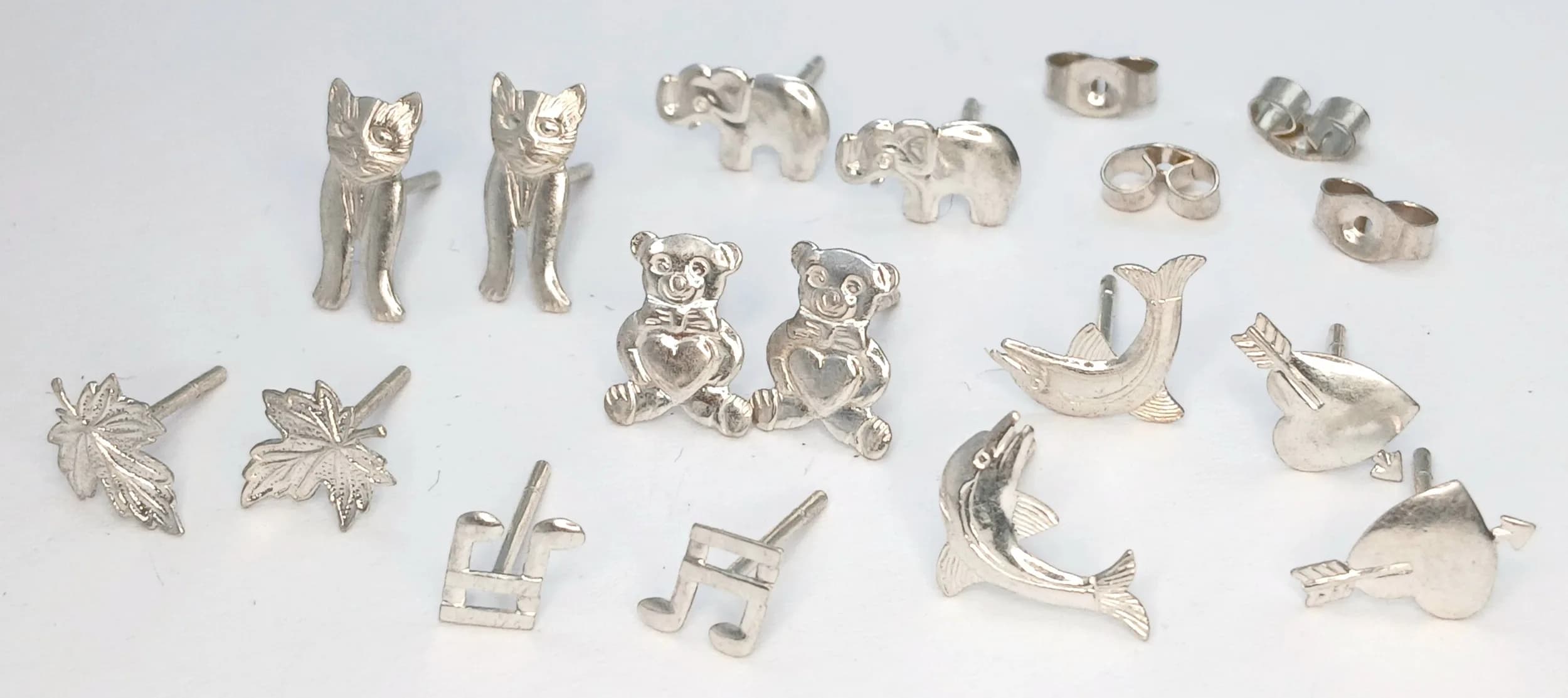 A COLLECTION OF 7 PAIRS OF STERLING SILVER, NOVELTY STUD EARRINGS. TO INCLUDE ELEPHANTS, MUSIC NOTE, TEDDY BEAR, LEAF, DOLPHINS, CAT AND HEART. INCLUDES 2 PAIRS OF SILVER BUTTERFLY BACKS ALSO. 2.6G. SC 7098